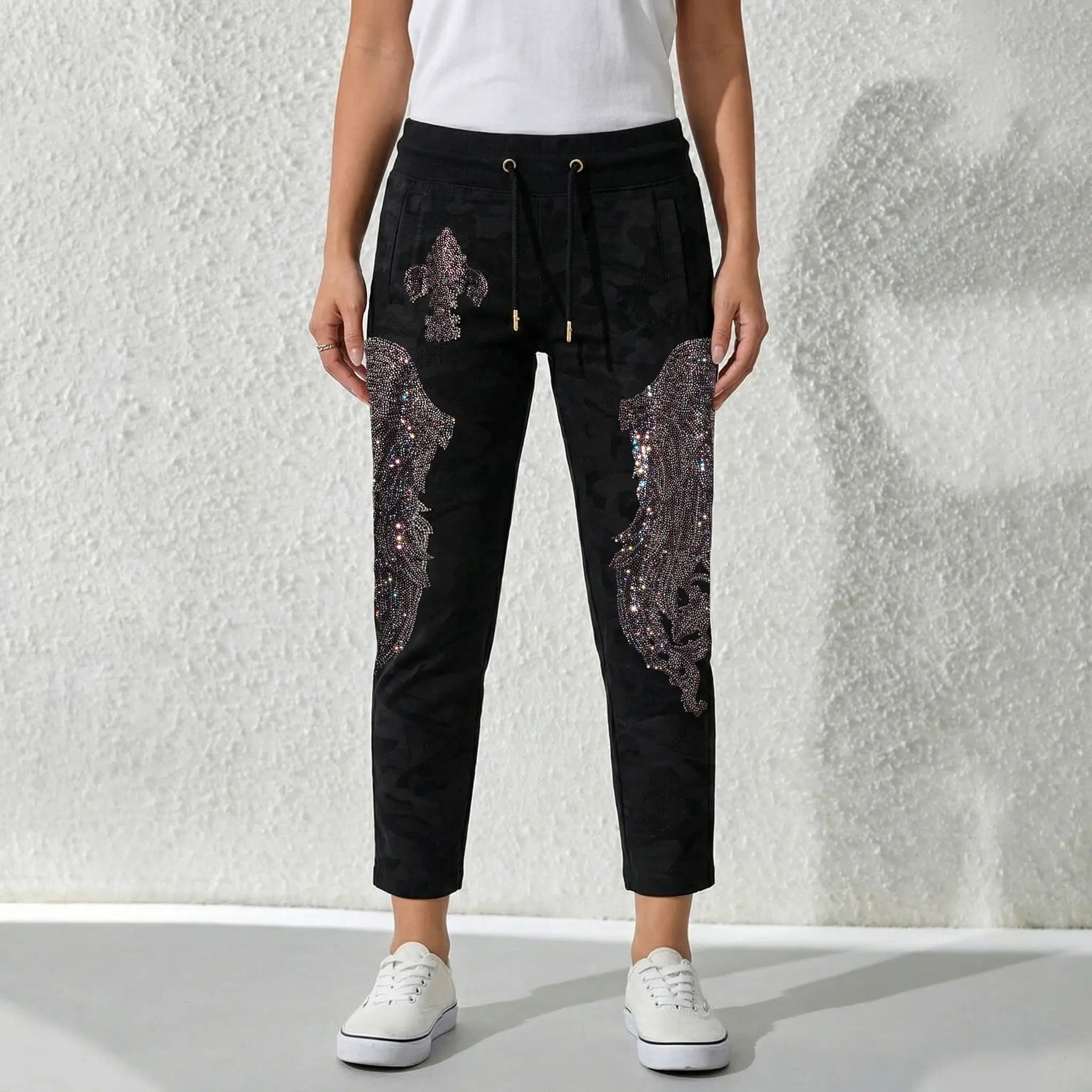 Person wearing black pants with sequin details against a textured white background, TCH Rhinestone Wing Camo Jogger Pants