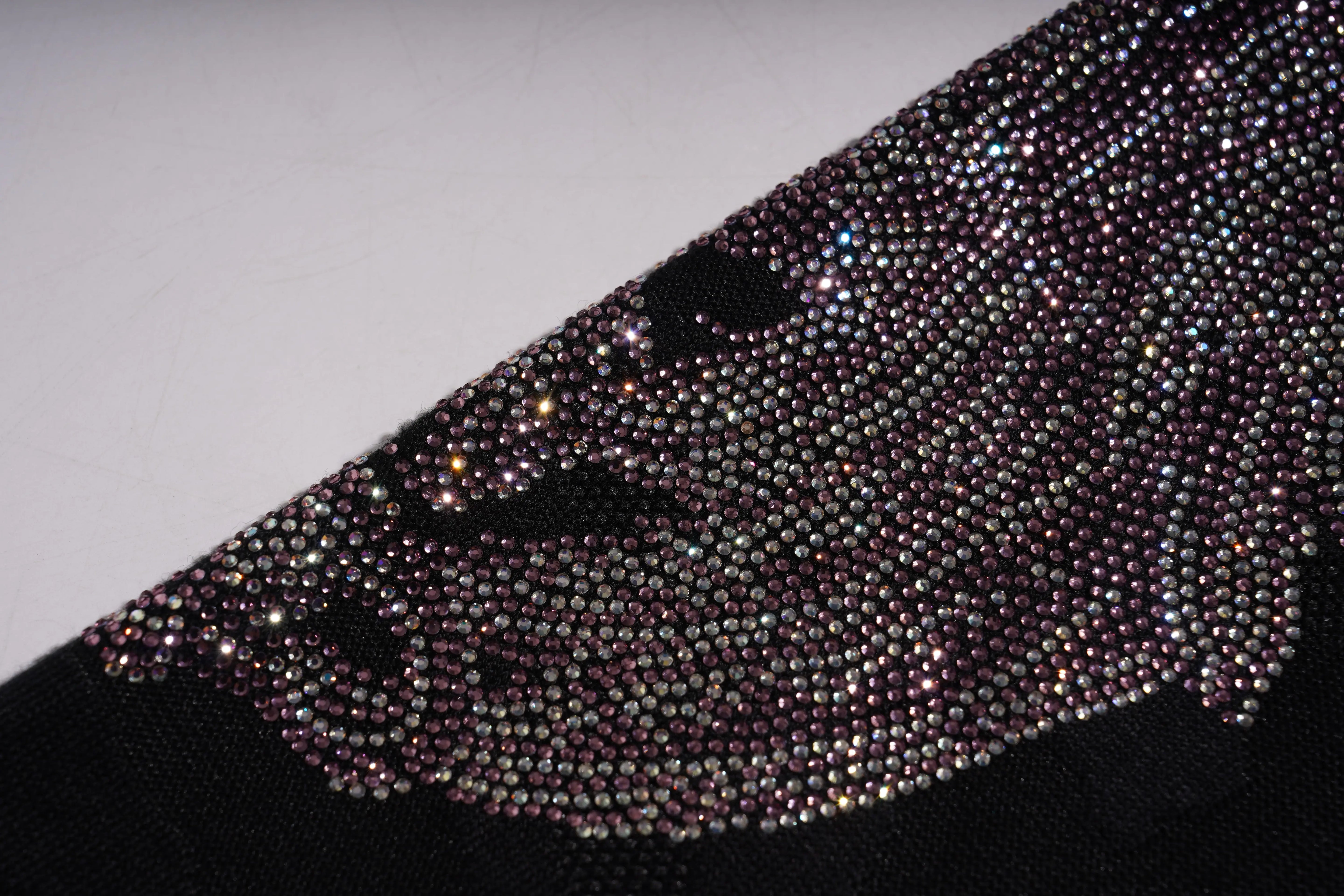 Close-up of a black clutch bag with sparkling rhinestone embellishments on a light gray background. TCH Rhinestone Wing Camo Jogger Pants