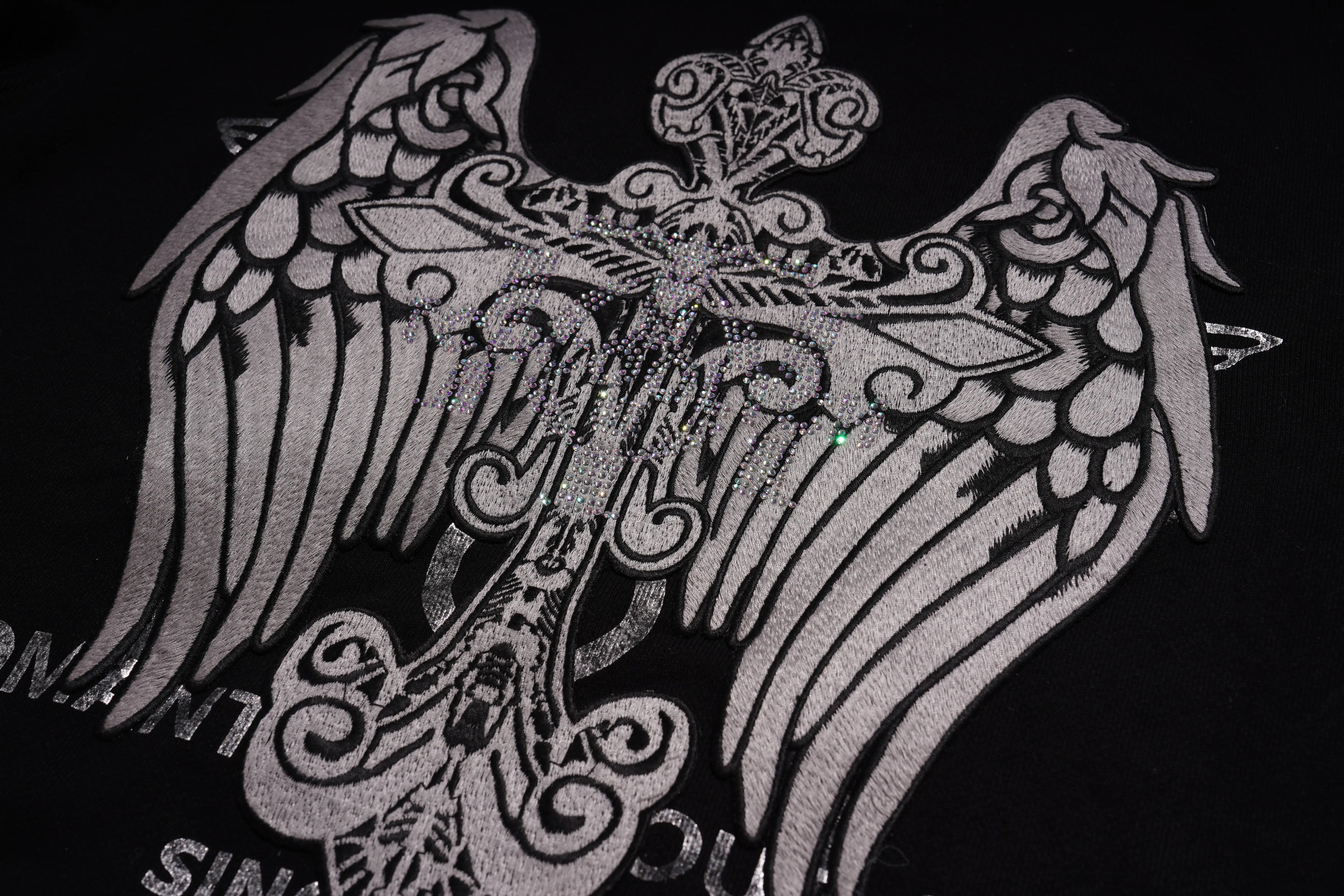 Decorative emblem with wings and intricate patterns on a black background, TCH Rhinestone Wing Crest Embroidered Sweatshirt