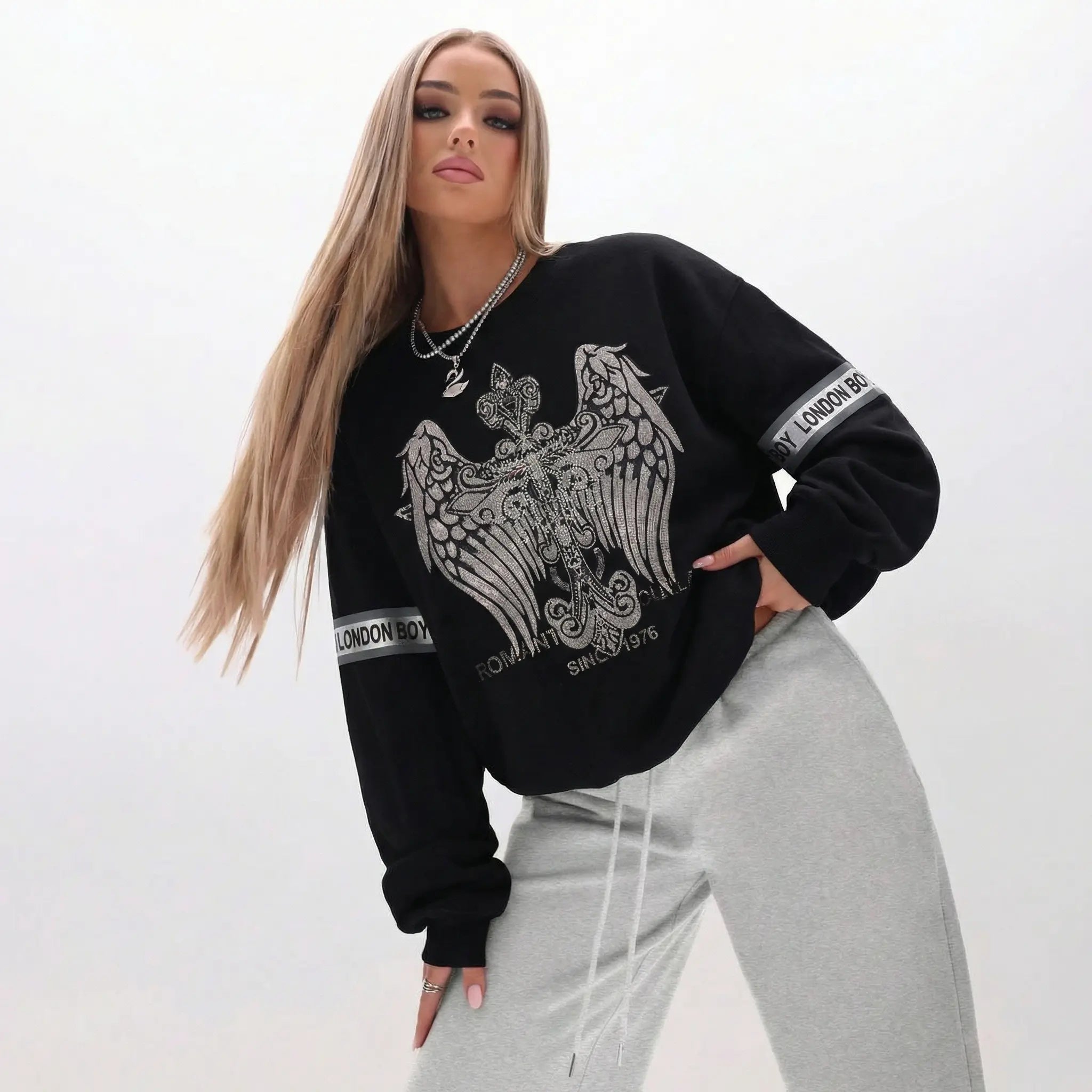 Woman wearing a black sweatshirt with a white eagle design on a plain background, TCH Rhinestone Wing Crest Embroidered Sweatshirt