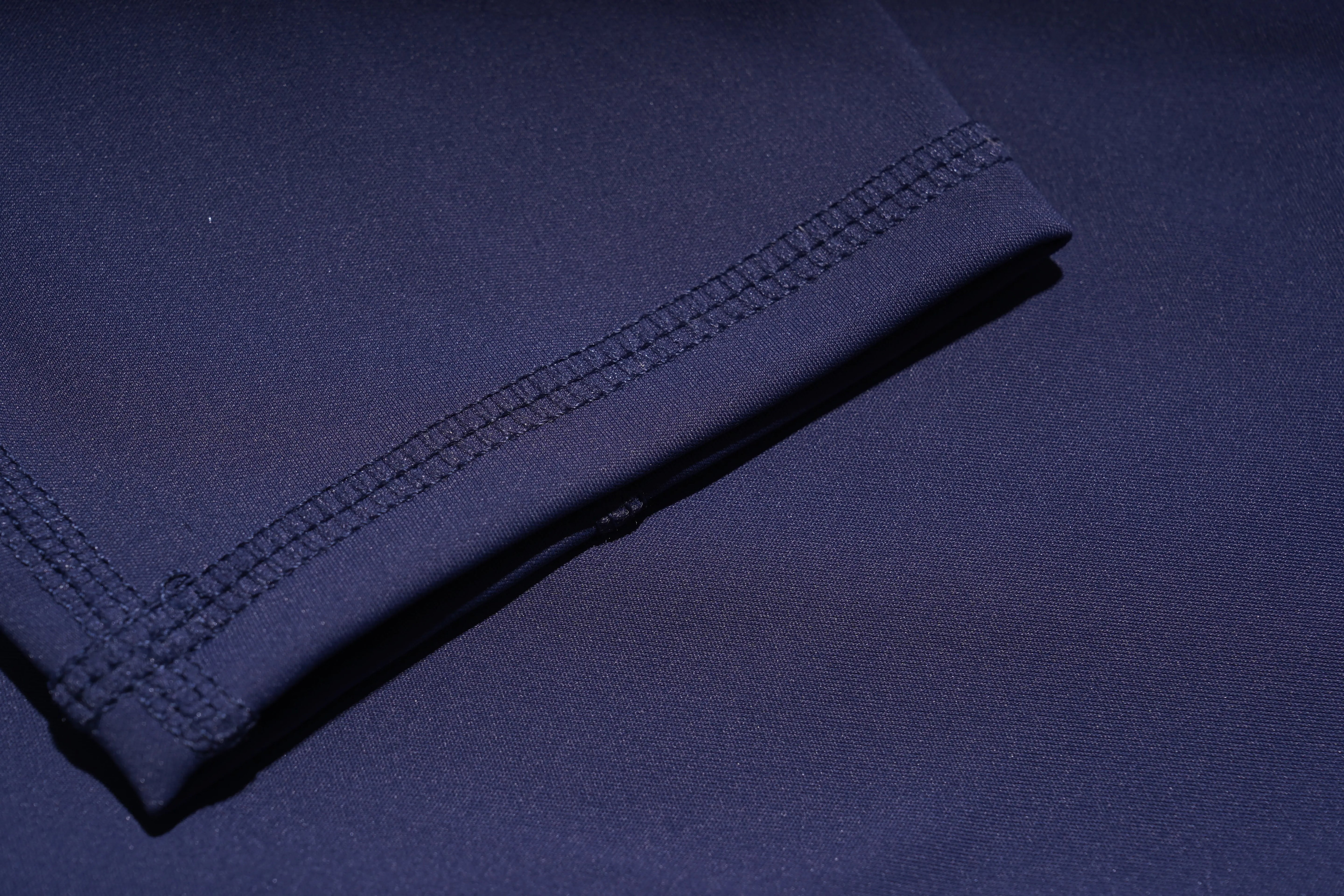 Folded navy blue fabric with visible stitching on a dark background