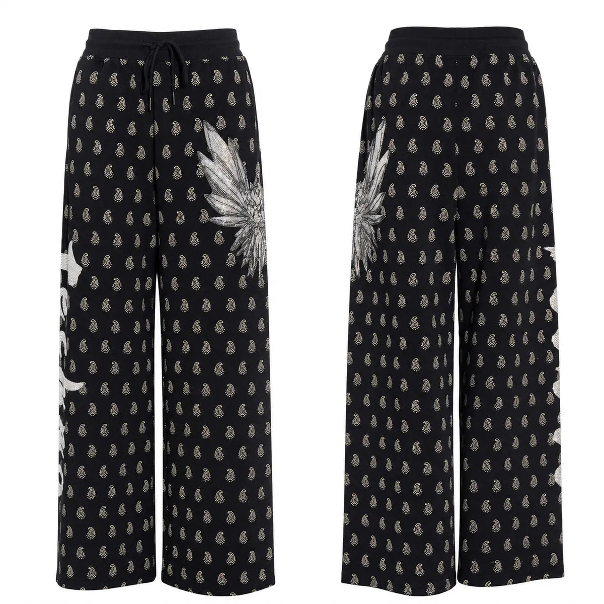 Black wide-leg pants with a repeating beige paisley pattern, featuring a large beige feather graphic on the left leg and a small beige patch detail on the right pocket, shown from both front and back views. TCH Rhinestone Wing Paisley Wide-Leg Sweatpants