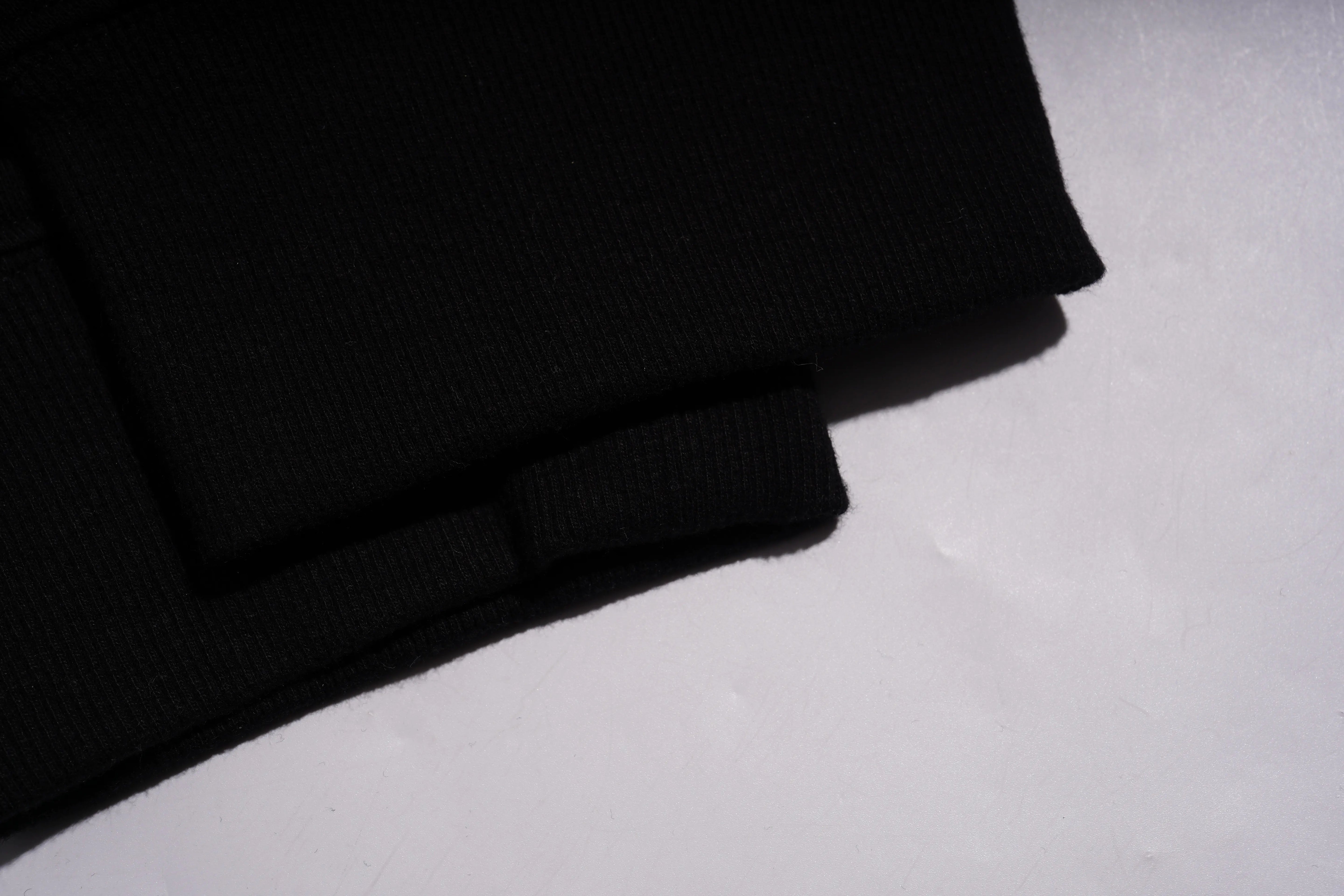 Folded black fabric on a light gray surface, TCH Rhinestone Wing Techno Jogger Pants
