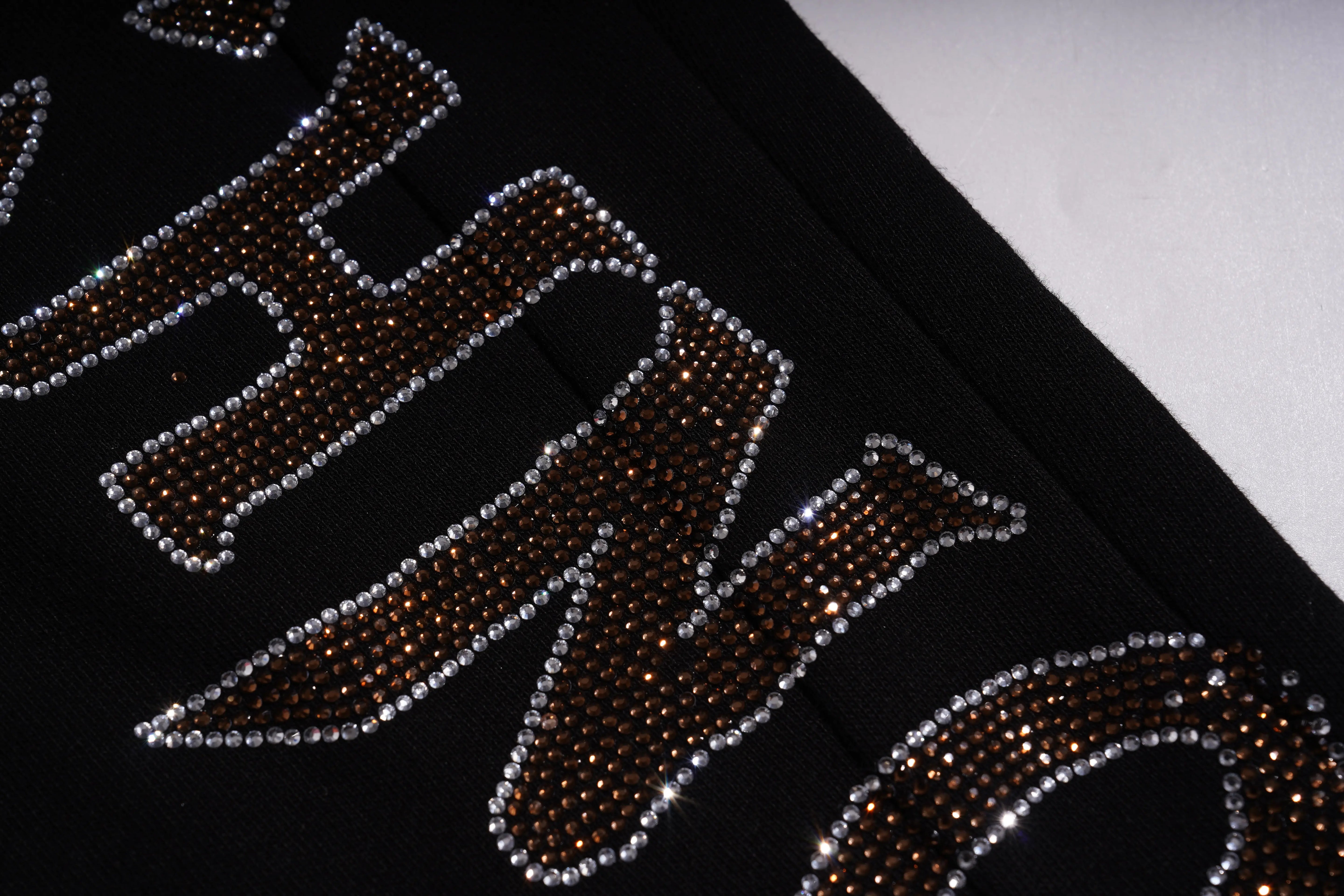 Close-up of a rhinestone-embellished text on a black background, TCH Rhinestone Wing Techno Jogger Pants