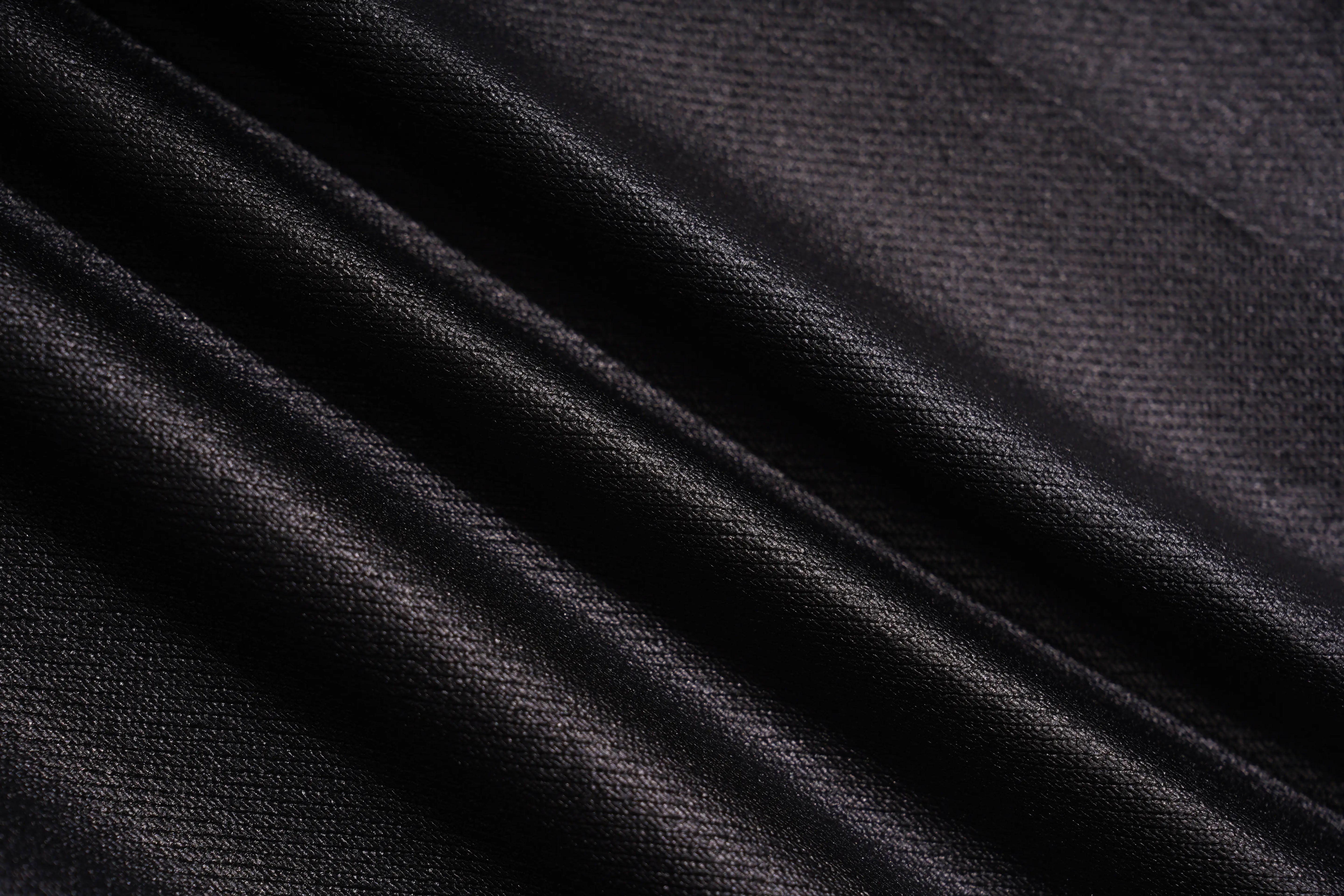 A close-up of draped black fabric with a fine textured weave, showing soft folds and subtle sheen. TCH Rhinestone Wing Teddy Faux Leather Jogger Pants
