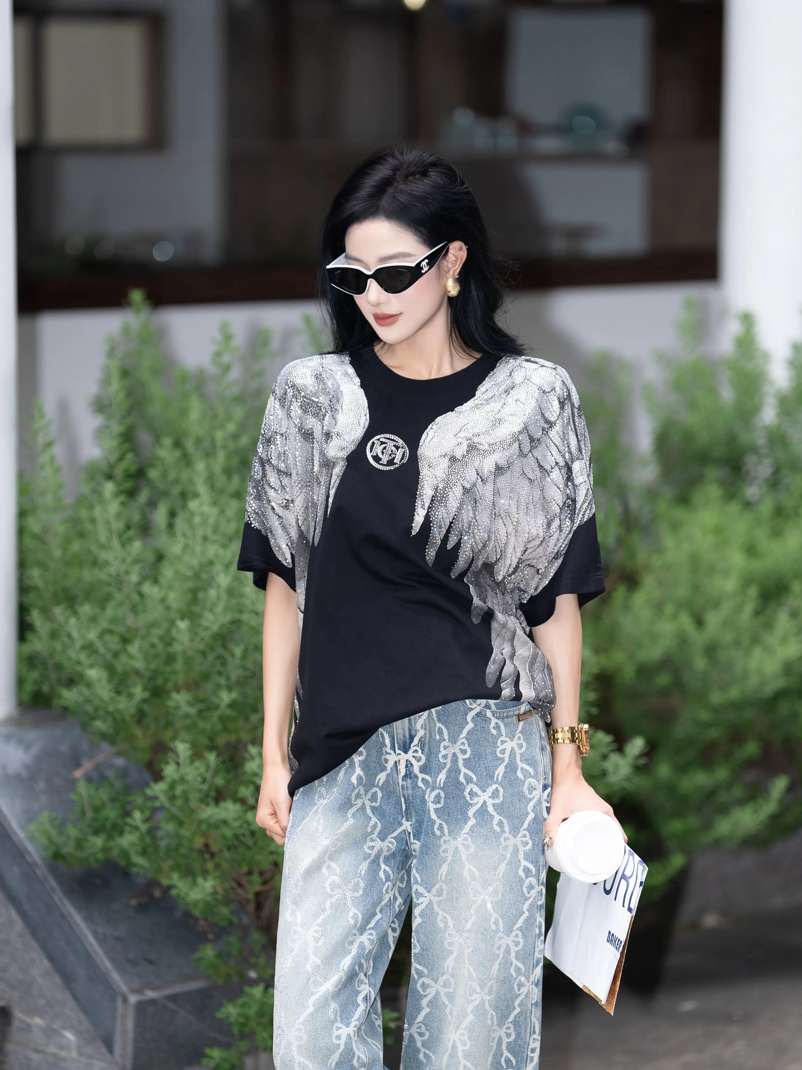Woman wearing a black and white patterned outfit with sunglasses outdoors. TCH Rhinestone Wings Logo Black Graphic T-Shirt