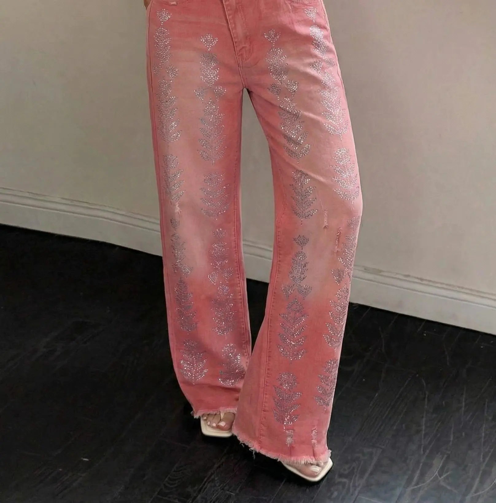 Pink jeans with glittery embellishments worn by a person on a dark floor. TCH Silver Bouquet Rhinestone Pink Denim Jeans