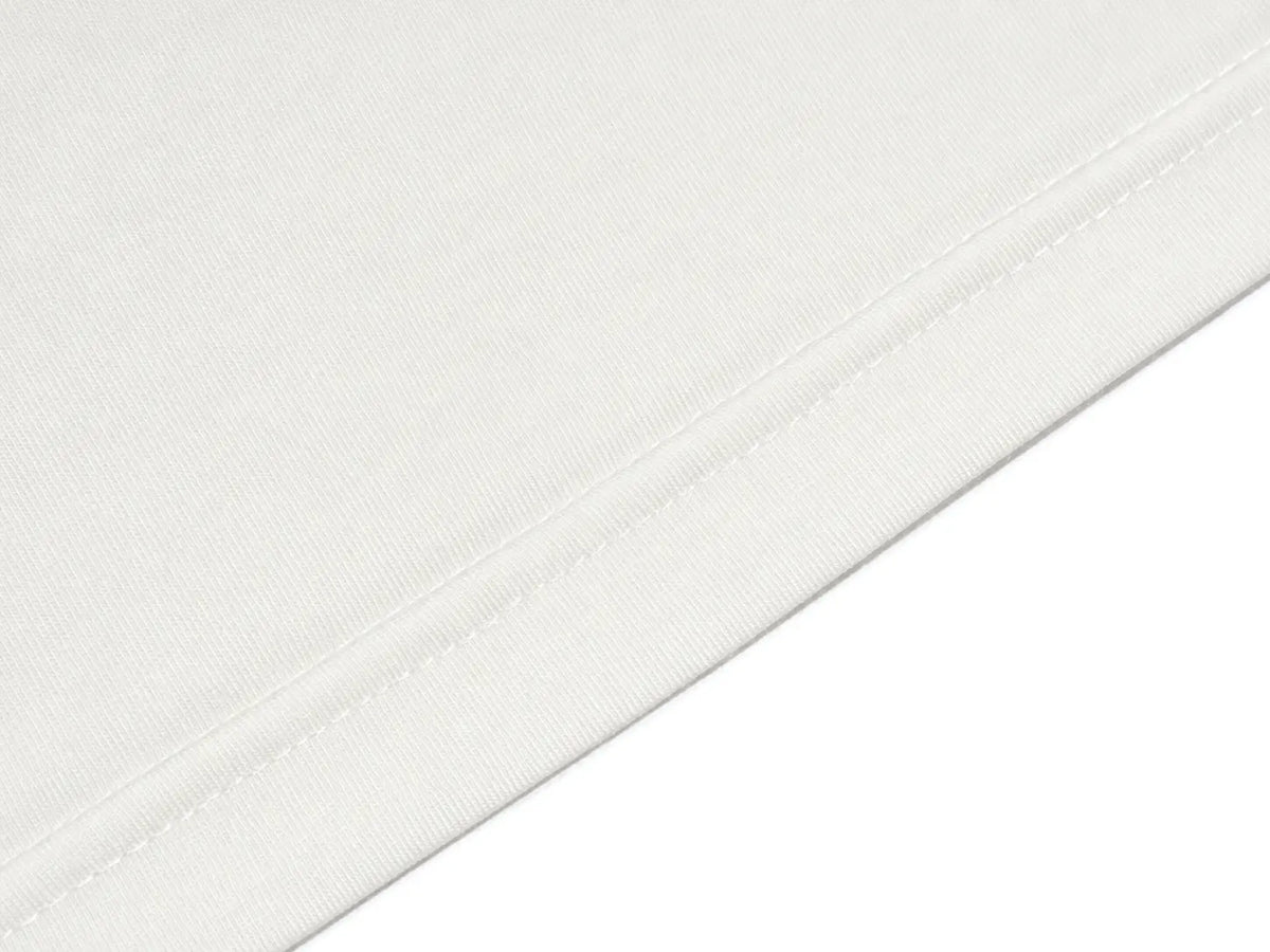 Close-up of a white fabric surface with a diagonal stitched seam on a white background. TCH Small Bear Angel Wings Rhinestone Graphic White Long Sleeve T-Shirt