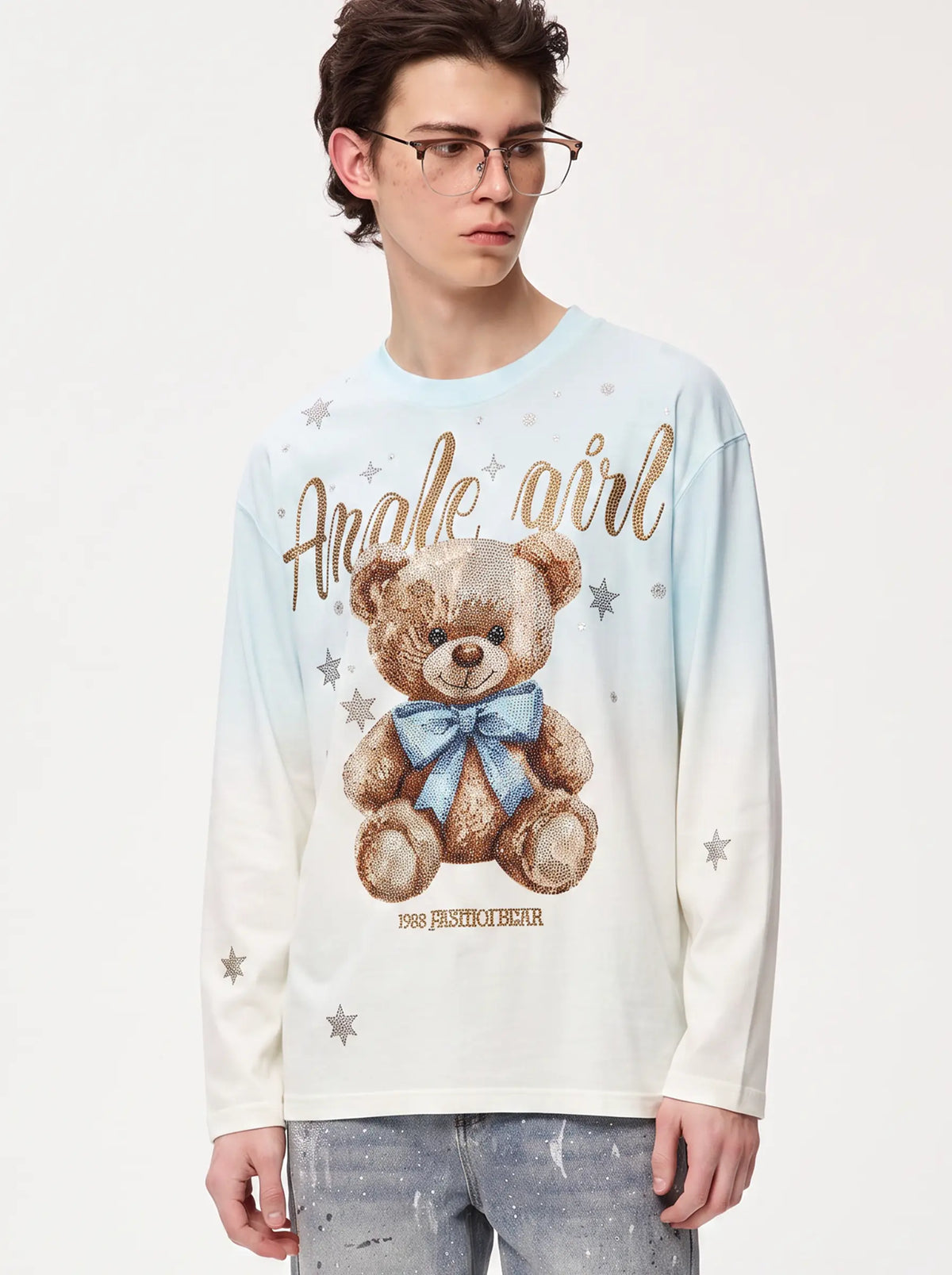 A young man wearing a light blue and white long-sleeve graphic t-shirt with a teddy bear print and the text 'Angie girl' and 'FASHION BEAR'. TCH Small Bear Angel Wings Rhinestone Graphic White Long Sleeve T-Shirt
