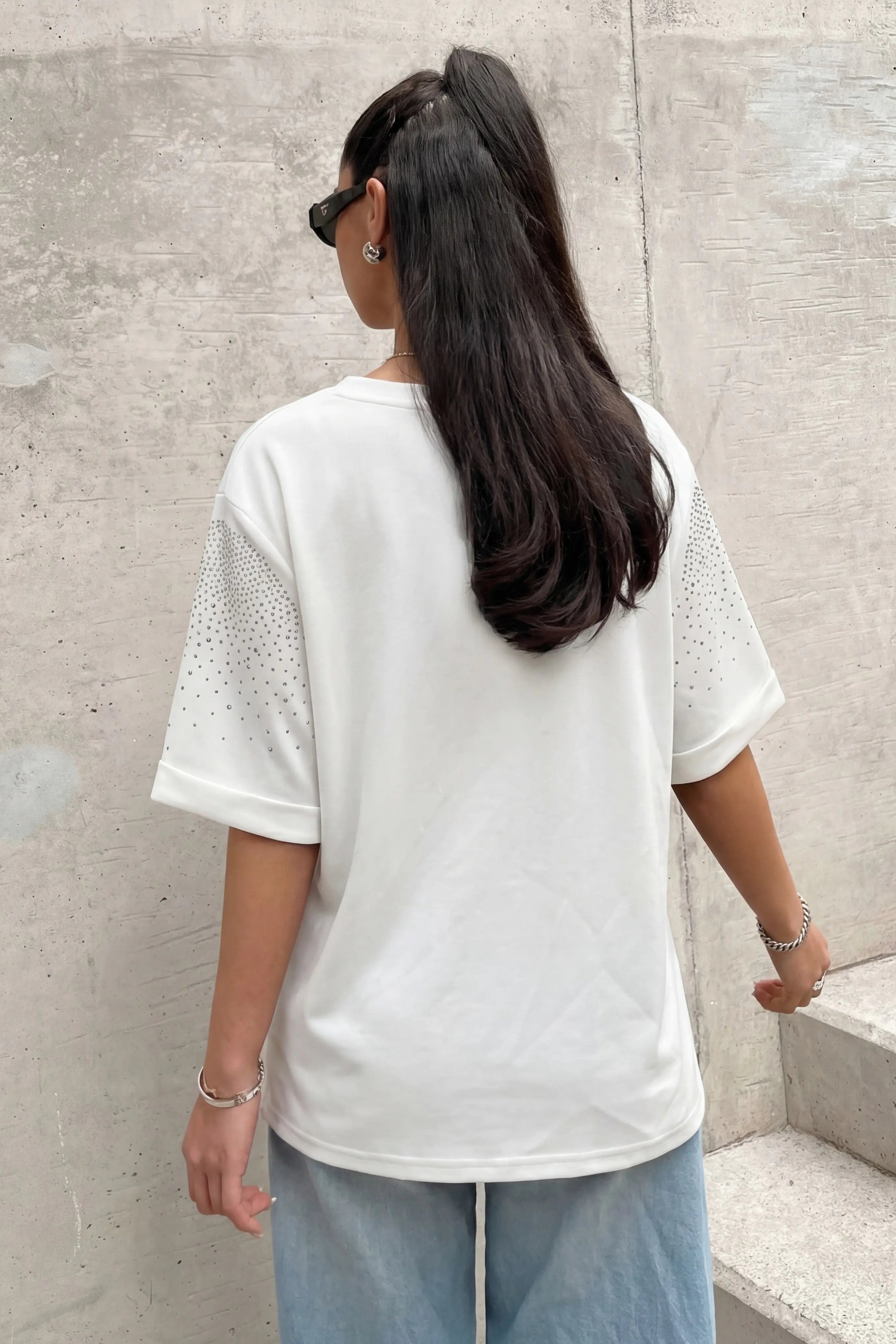 Person wearing a white t-shirt and light blue jeans standing on concrete steps against a concrete wall. TCH Starry Gradient Rhinestone Butterfly T-Shirt