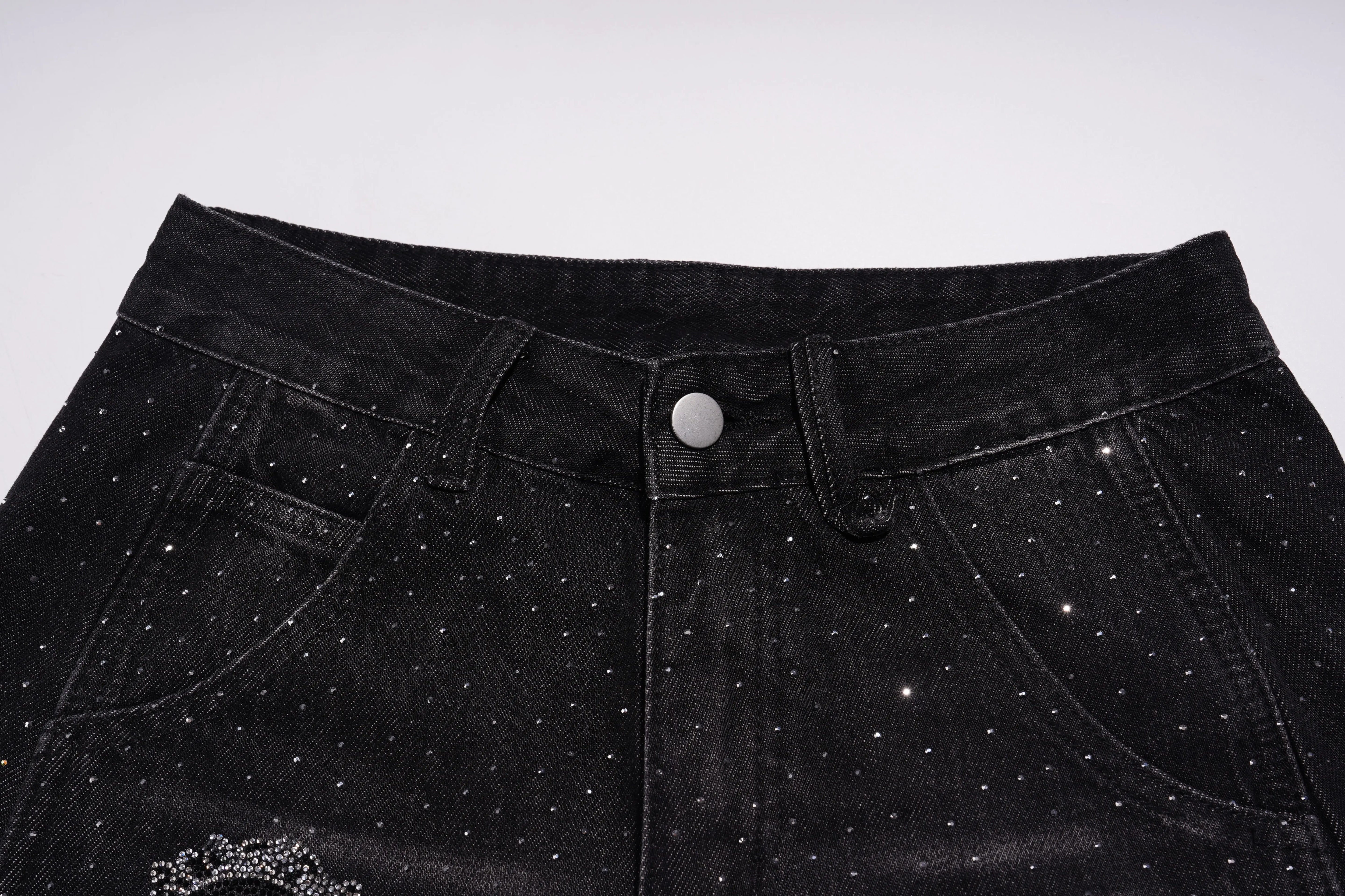 Close-up of black pants with rhinestone embellishments on a white background, TCH Starry Rhinestone Logo Black Denim Jeans