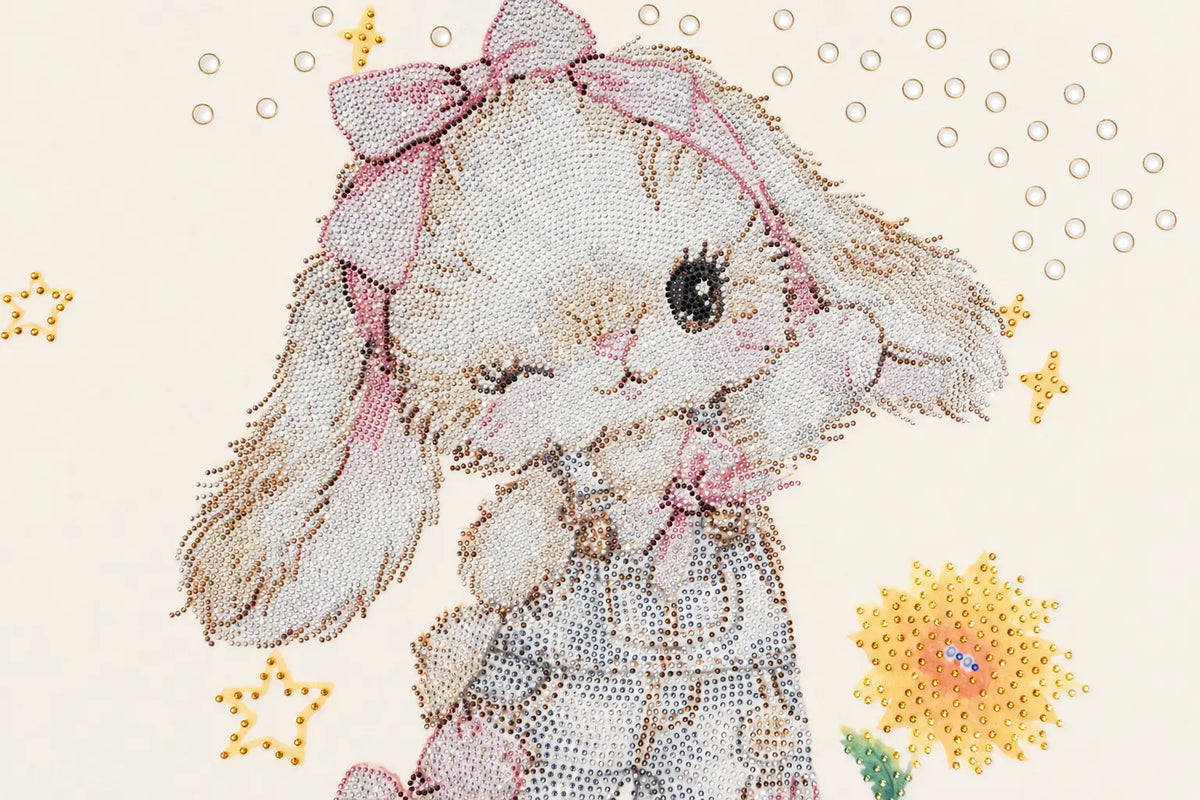 A close-up of a diamond painting or bead art design depicting a cute white bunny with long floppy ears, a pink bow, and a pink dress, surrounded by small yellow stars and flowers on a light cream background. TCH Sweet Bunny Rhinestone Graphic Long Sleeve Top