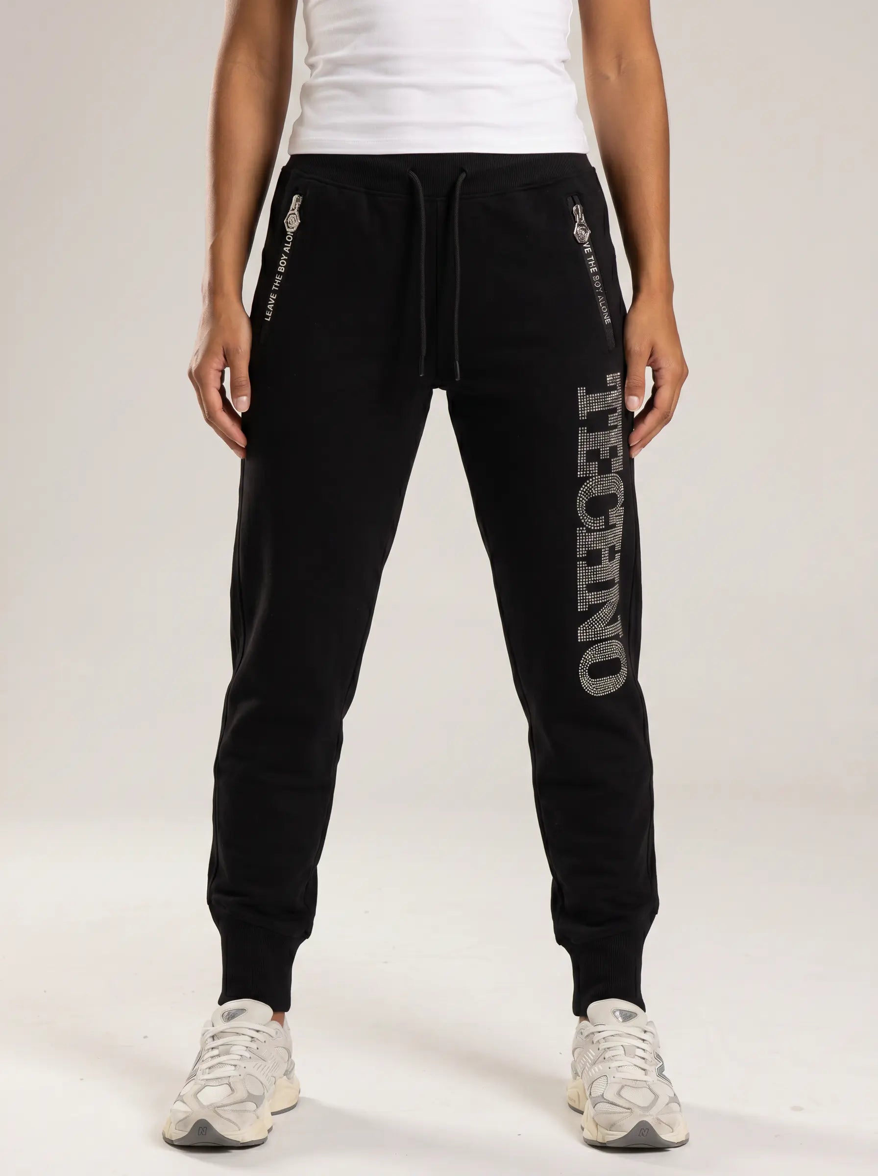 Person wearing black jogger pants with branding on a white background, TCH TECHNO Rhinestone Jogger Pants