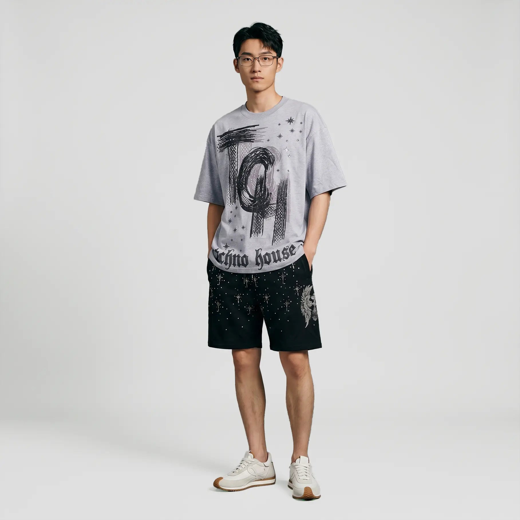 A man modeling a light gray graphic t-shirt with black distressed print and black shorts, paired with white sneakers, against a plain light gray studio background. TCH Techno House Abstract Graphic Oversized T-Shirt