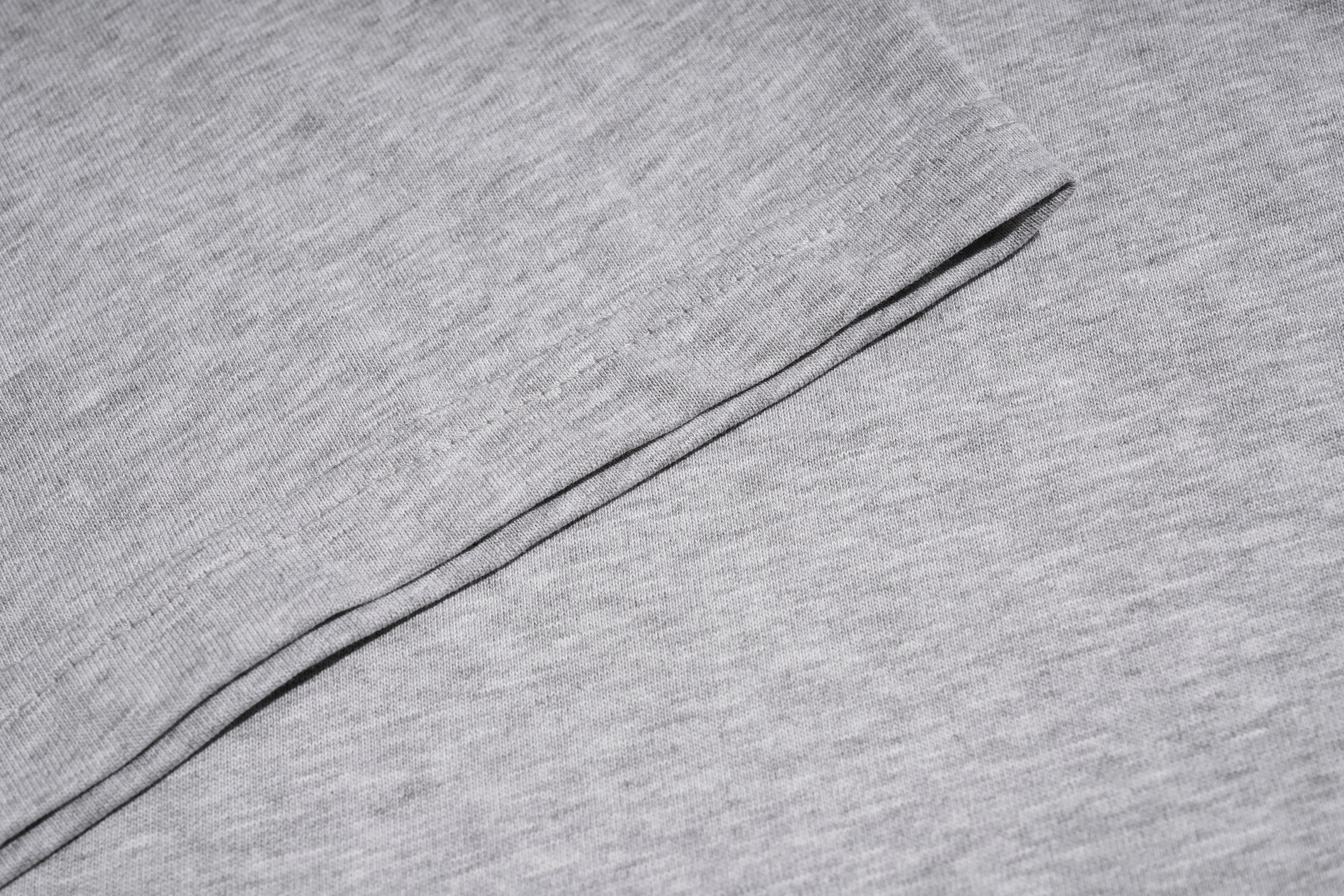 Close-up of a light gray heathered fabric with a diagonal black stitched seam. TCH Techno House Abstract Graphic Oversized T-Shirt