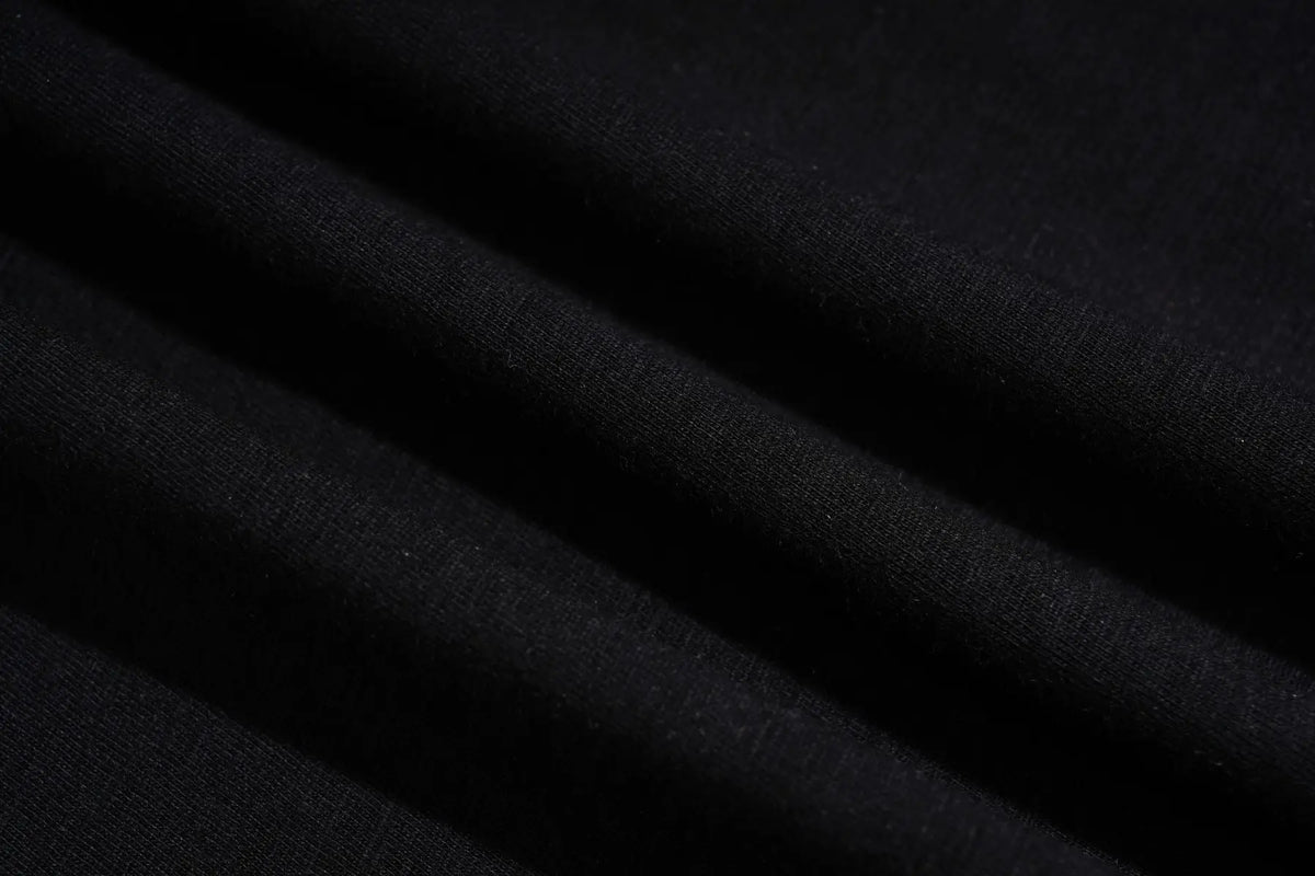 A close-up of draped black fabric with soft folds showing a fine knit texture. TCH Techno Rhinestone Gothic Graphic Black T-Shirt