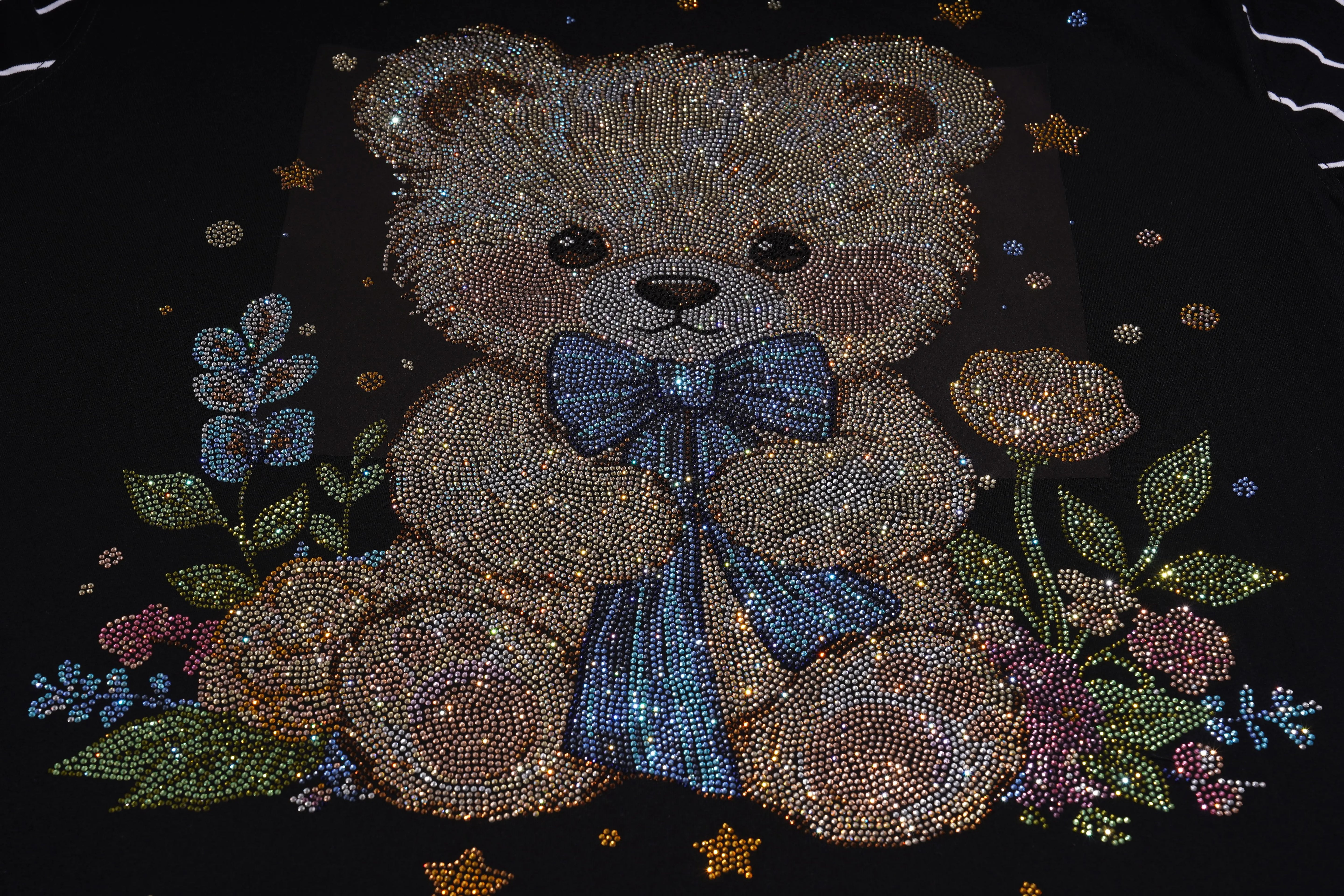 Decorative teddy bear with a blue bow surrounded by flowers on a dark background, TCH Teddy Bear & Stars Rhinestone T-Shirt