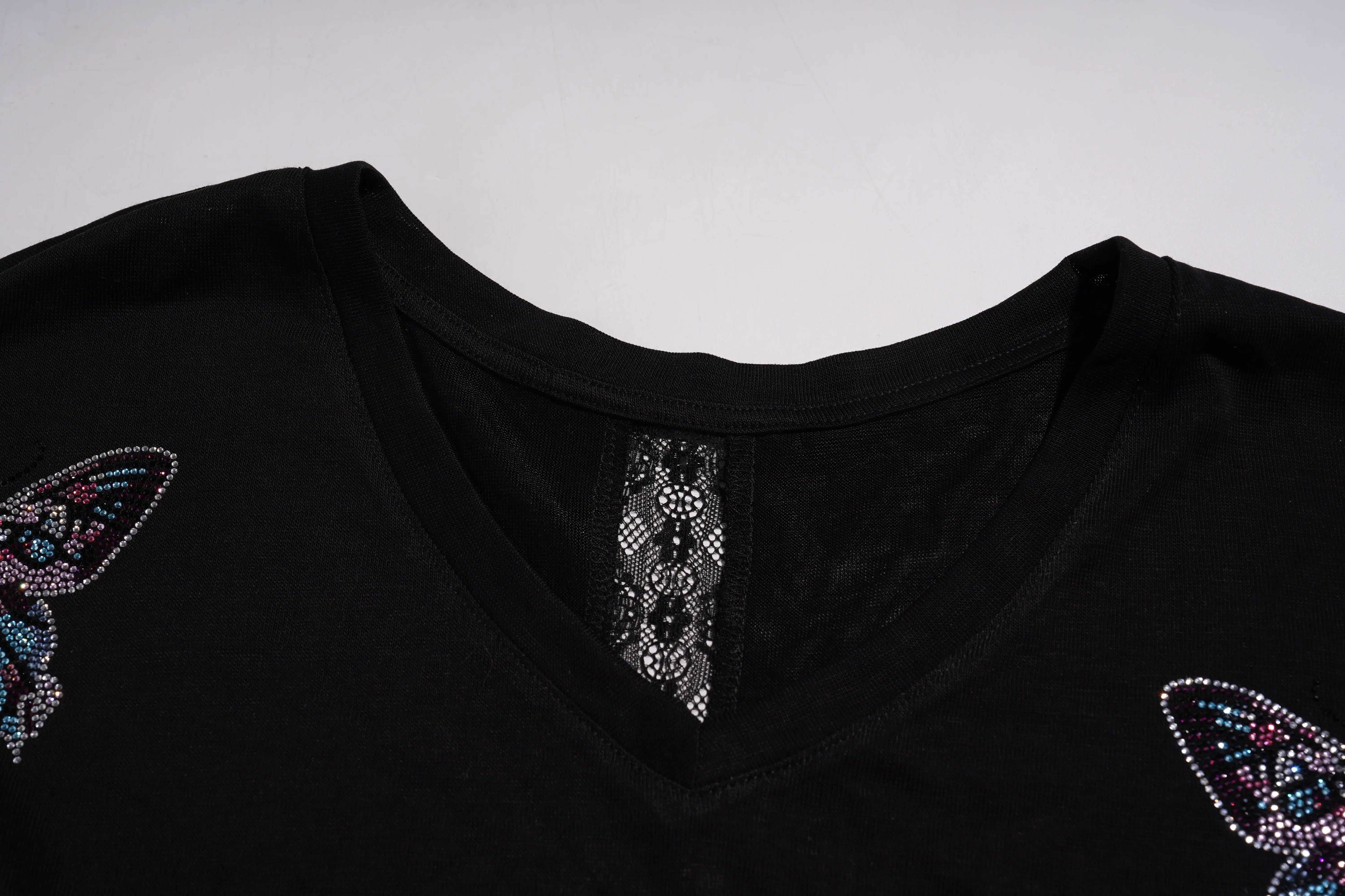 Black garment with butterfly designs and embellishments on a light gray background, TCH V-Neck Rhinestone Butterfly Long Sleeve Top