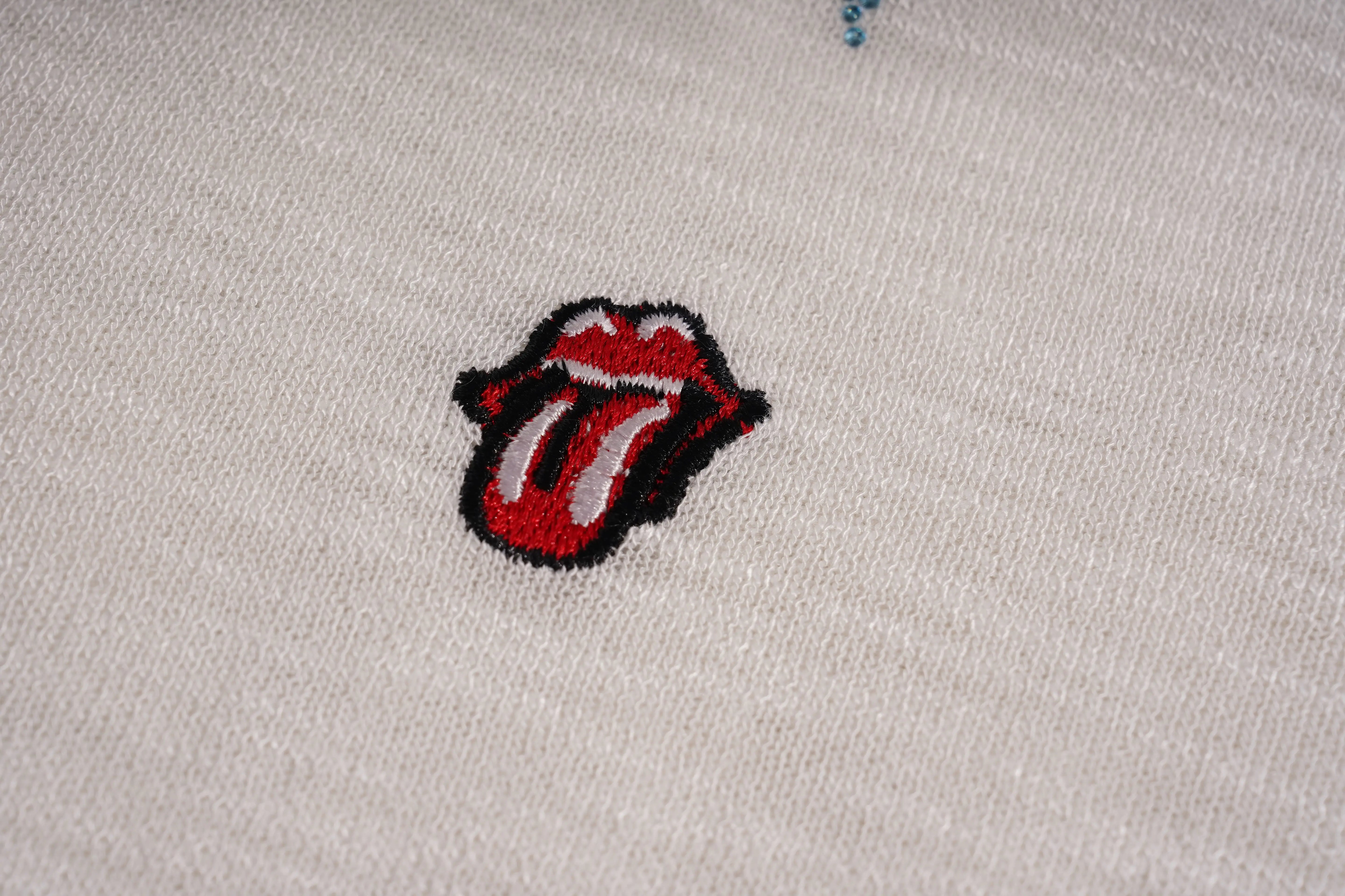 Embroidered Rolling Stones logo on a beige fabric background, TCH White Rhinestone Bow Knit Cardigan