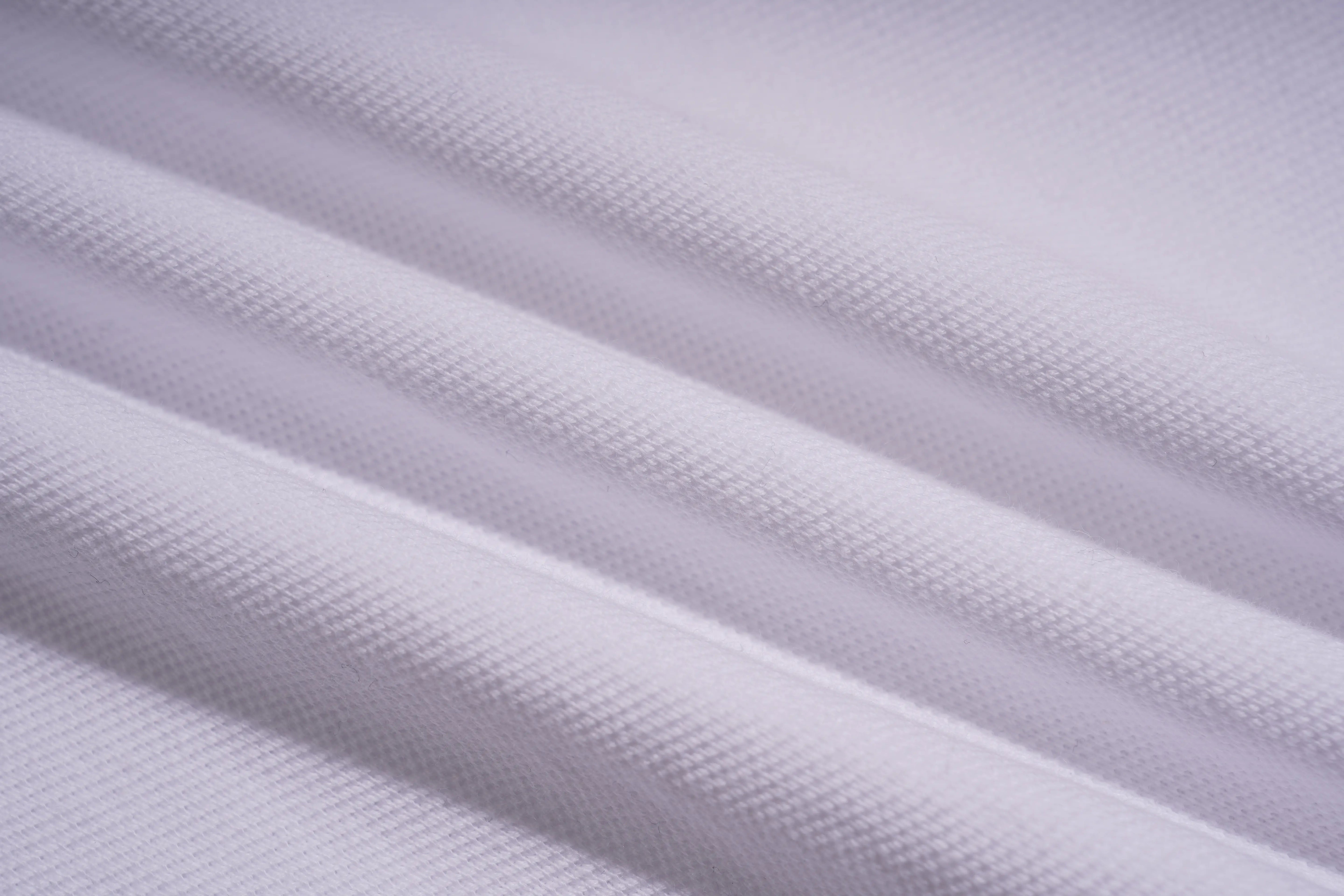 A close-up of white textured fabric with soft diagonal folds and a fine woven pattern. TCH White Teddy Bear Embellished Polo Shirt