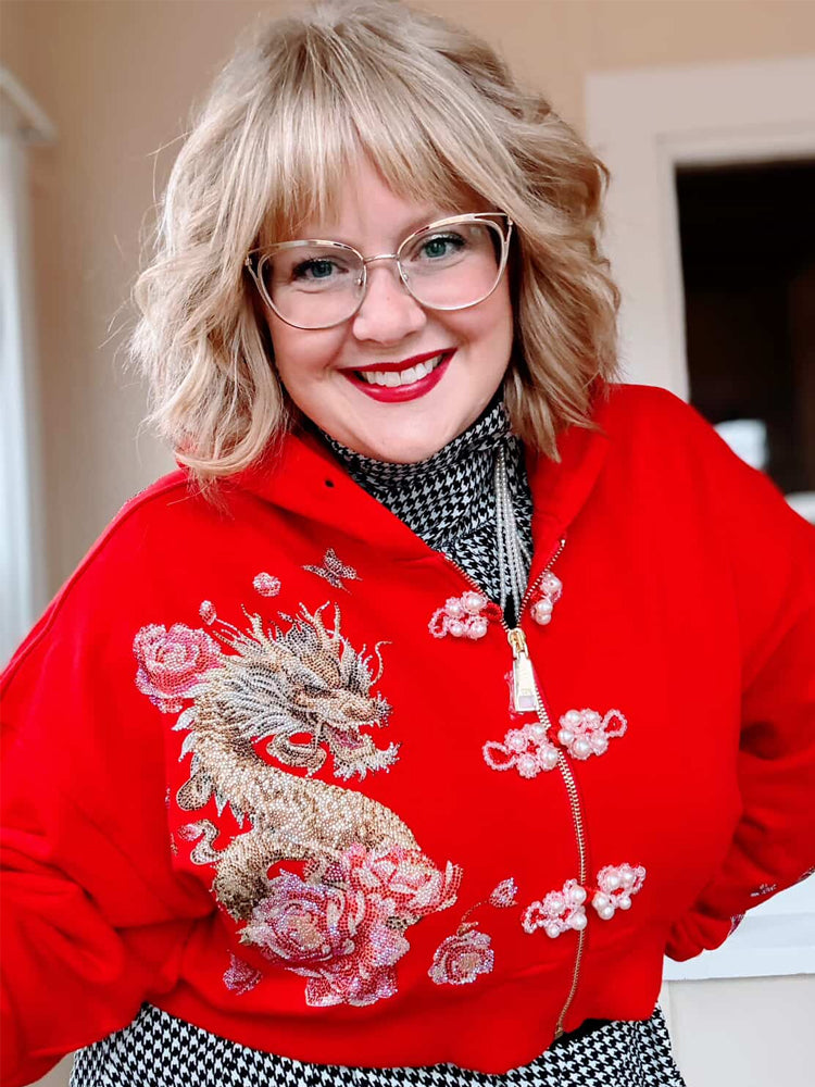 Person wearing a red hoodie with a dragon design indoors
