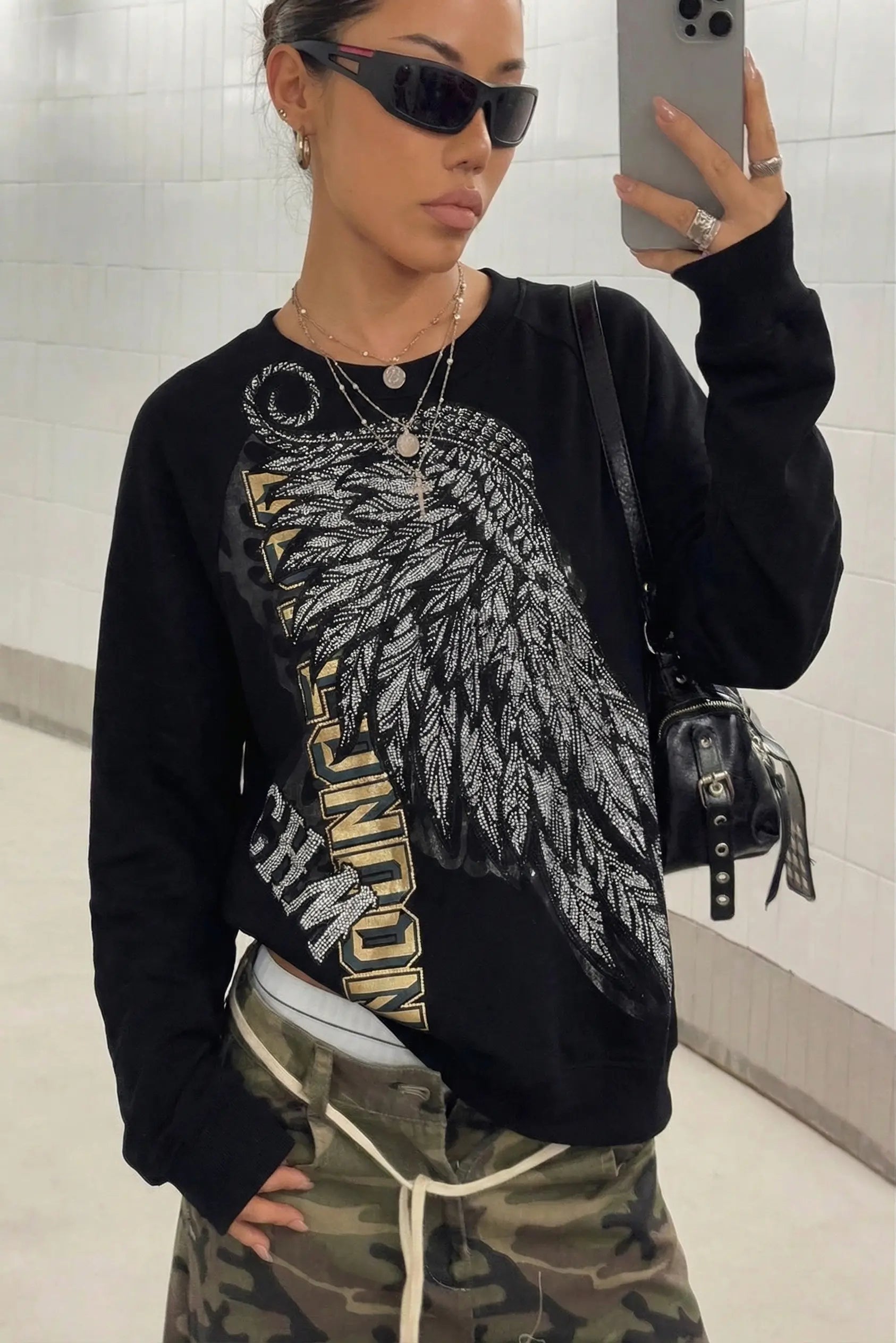 Person wearing a black sweatshirt with a graphic design, taking a mirror selfie. Rhinestone Wing Embroidered Sweatshirt
