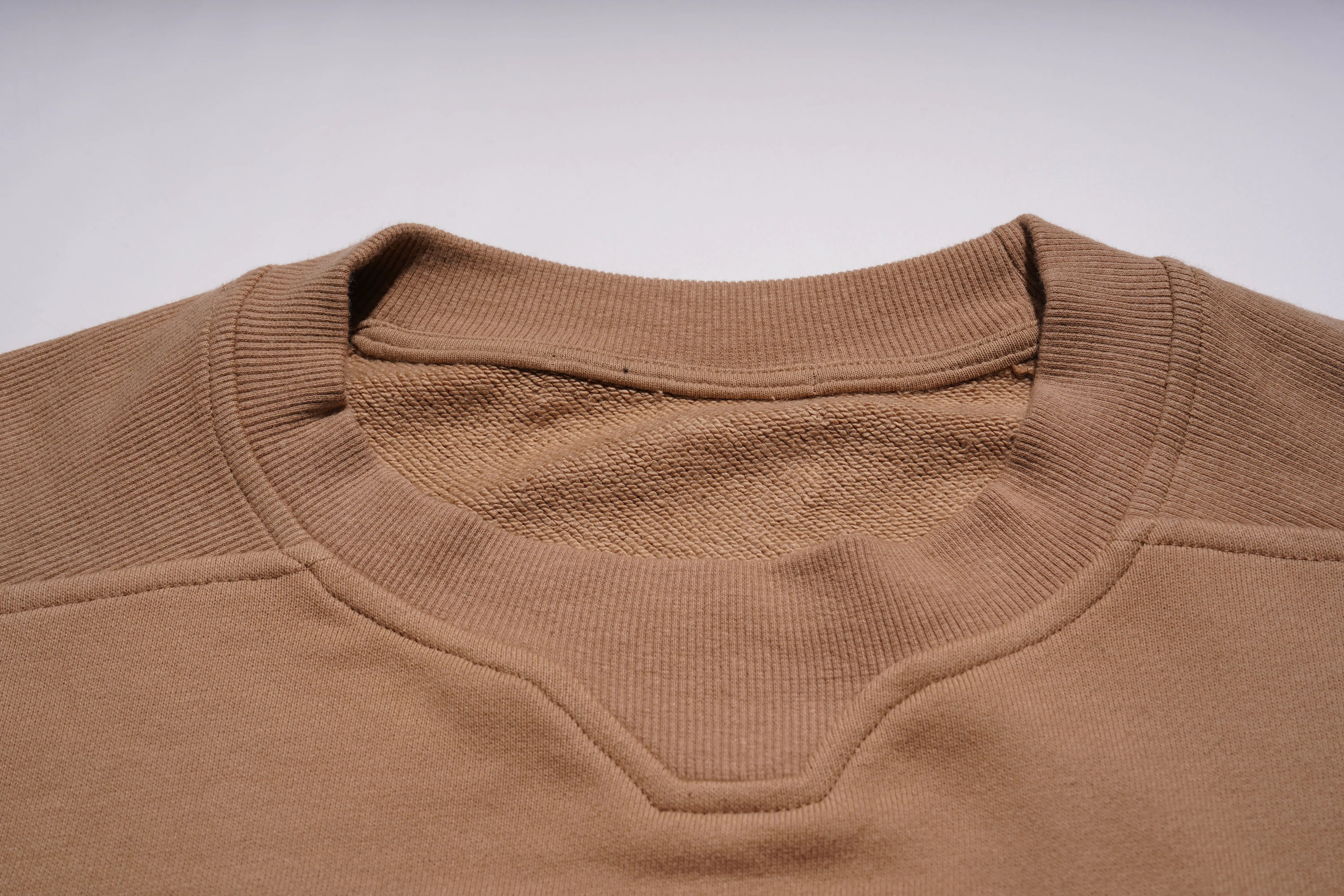 Close-up of a brown sweater collar on a light gray background