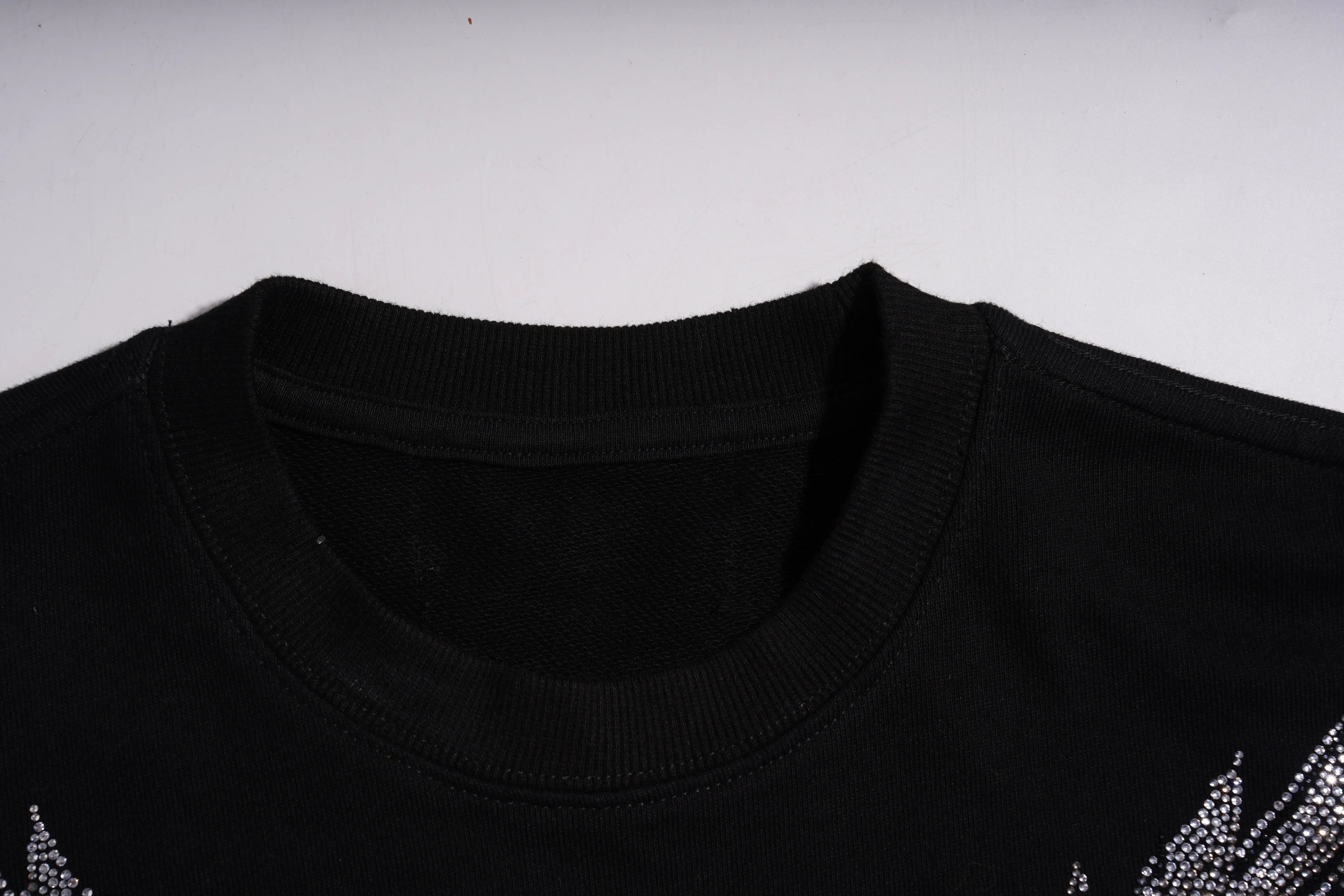 Close-up of a black shirt collar with a white background, TCH 1976 Rhinestone Wings Sweatshirt