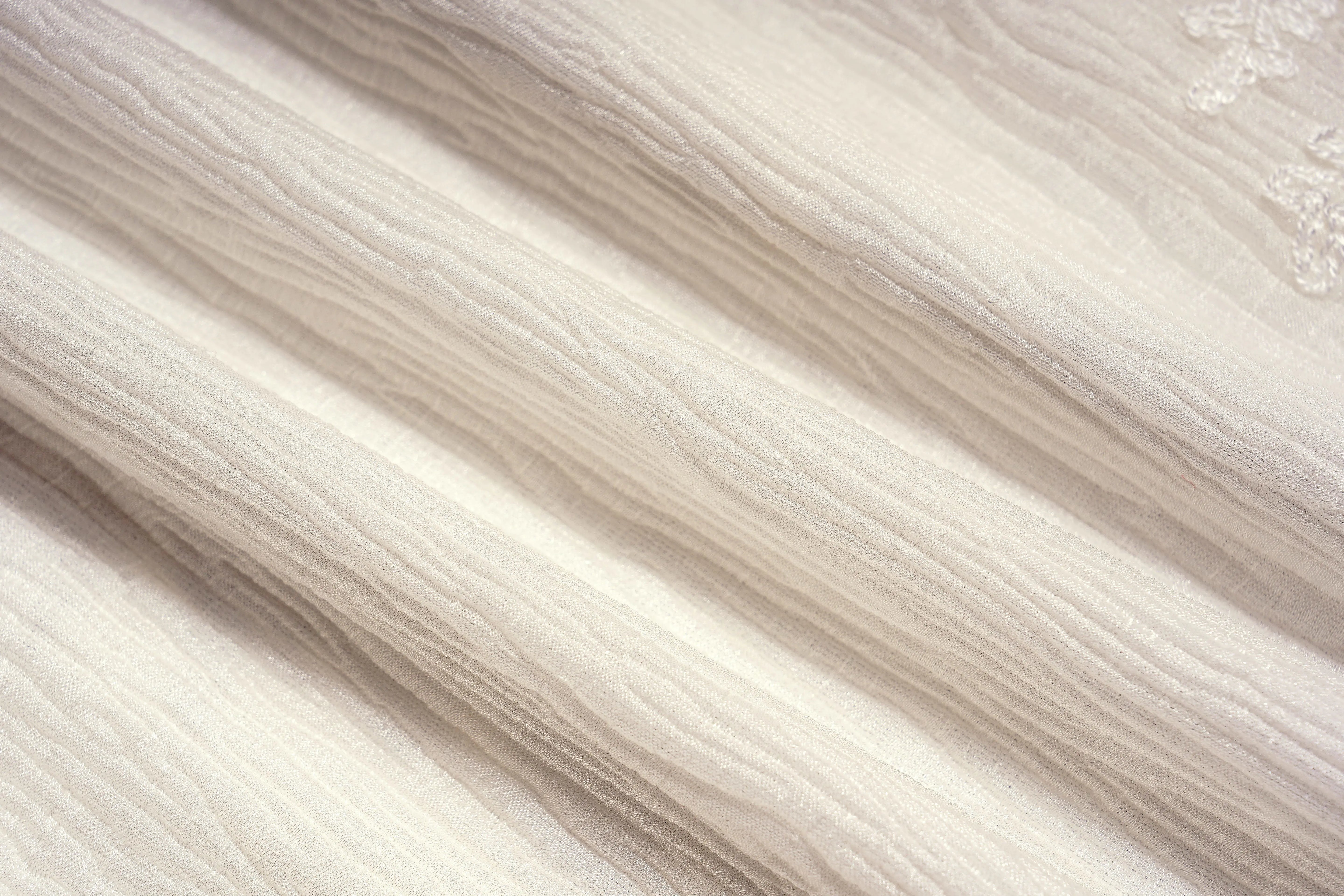 Close-up of beige fabric texture, TCH Angel Wings Rhinestone Ruffle Blouse