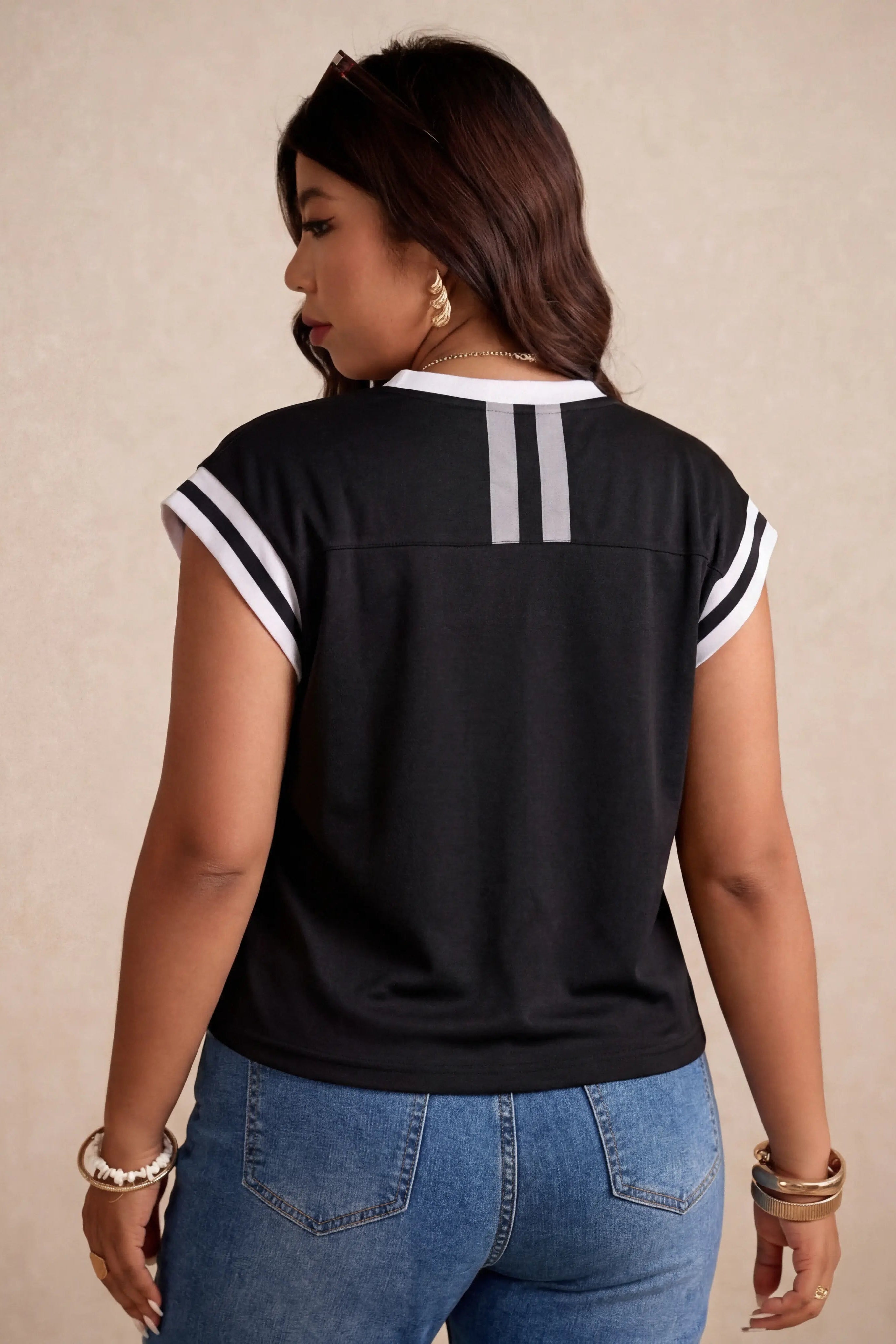 Woman wearing a black and white top with blue jeans on a beige background, TCH Angel Wings Rhinestone V-Neck Tee