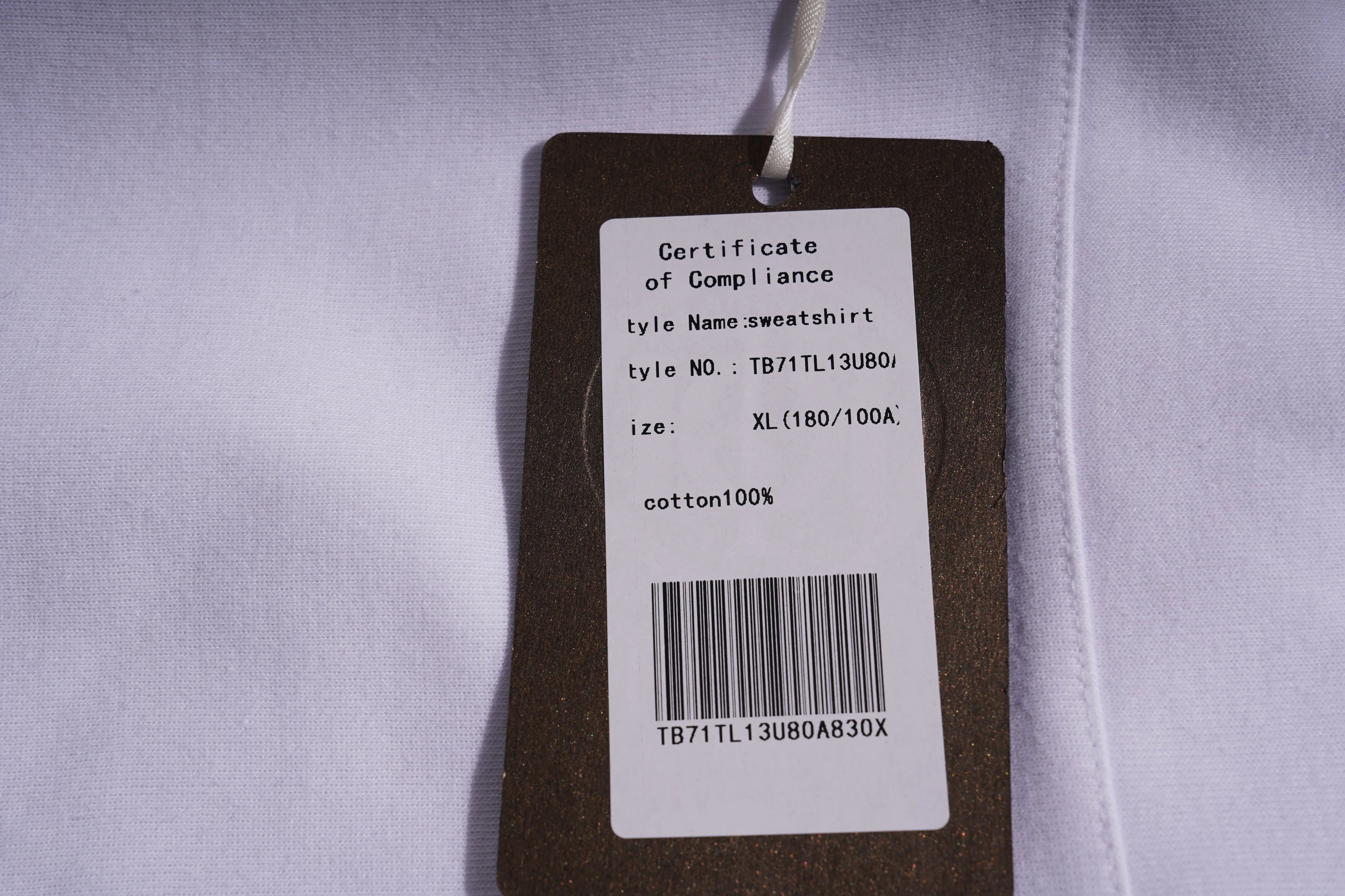 Clothing tag with certificate of compliance details on a white shirt.