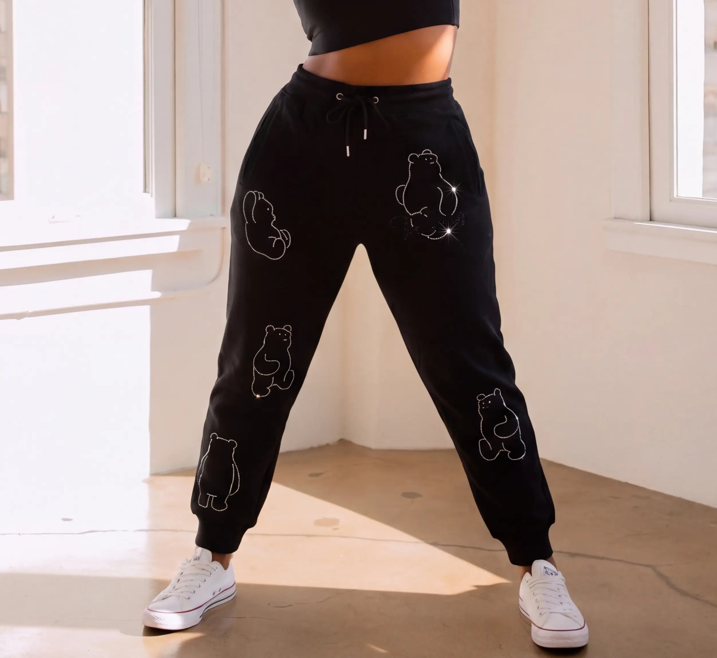 Person wearing black sweatpants with bear prints in a bright room. TCH Bear Sketch Rhinestone Jogger Pants