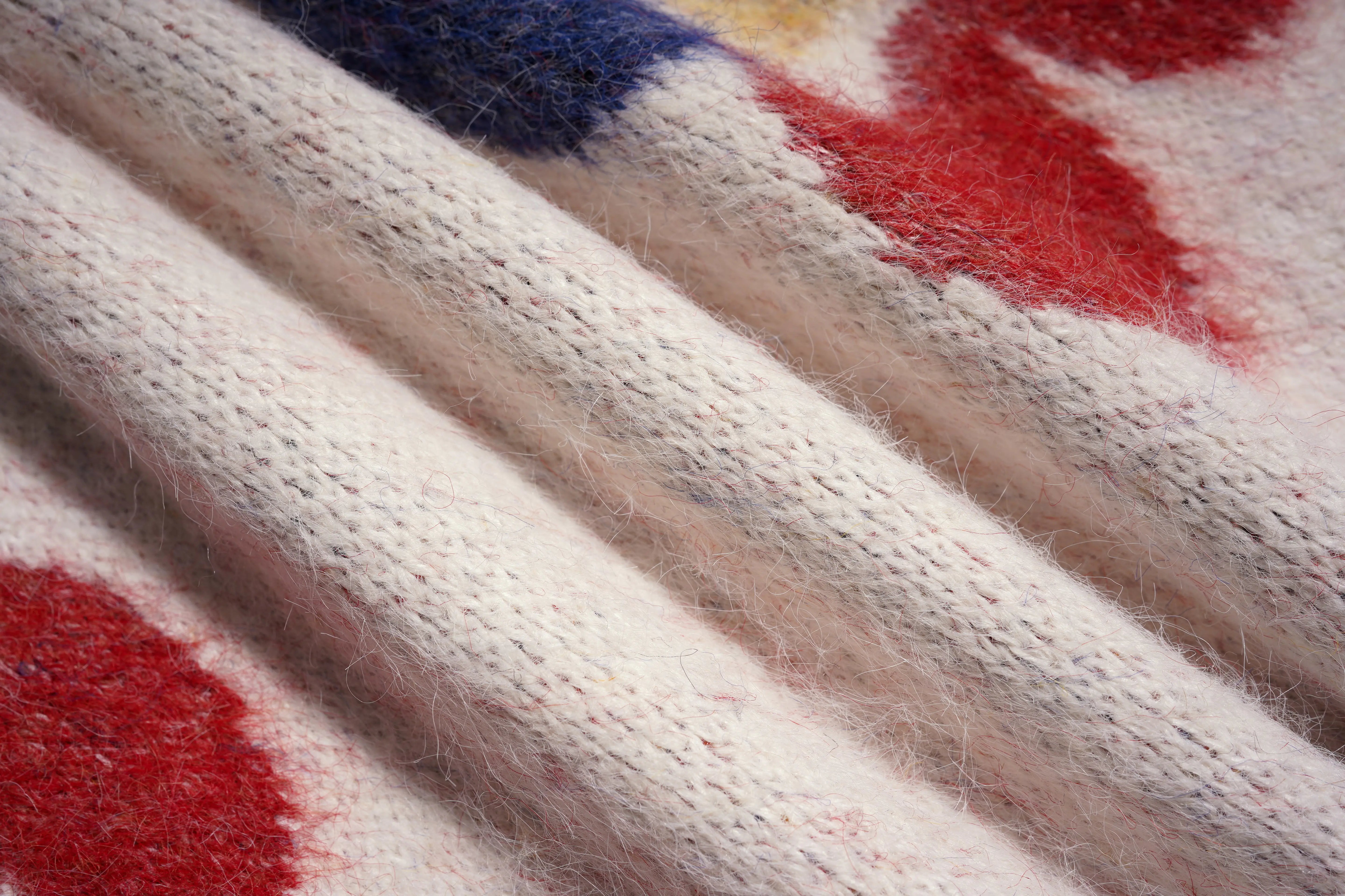 Close-up of a textured fabric with red and blue patterns, TCH Beige Floral Rhinestone V-Neck Sweater & Wool Mini Skirt Set