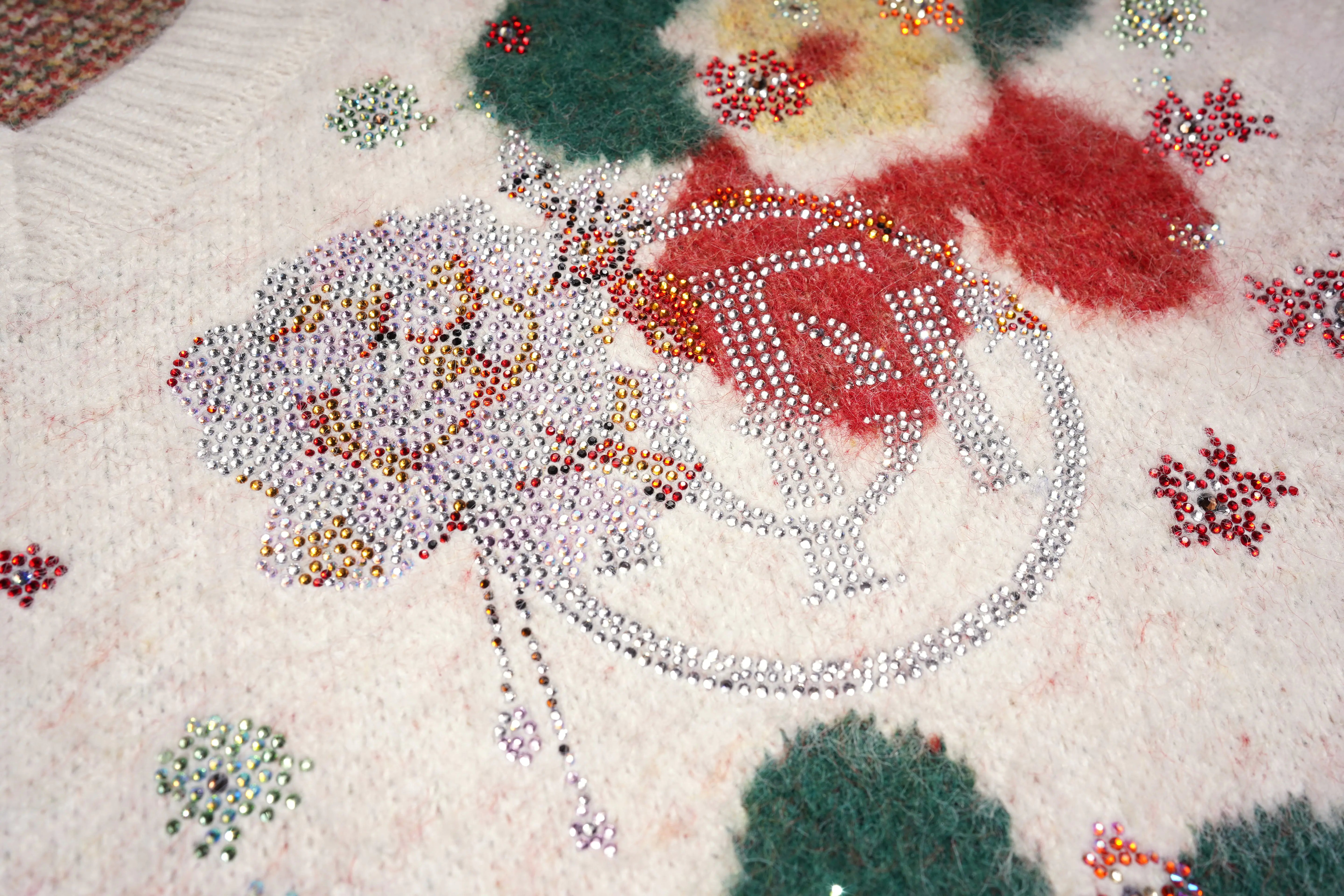 Close-up of a textured surface with floral patterns and beadwork. TCH Beige Floral Rhinestone V-Neck Sweater & Wool Mini Skirt Set