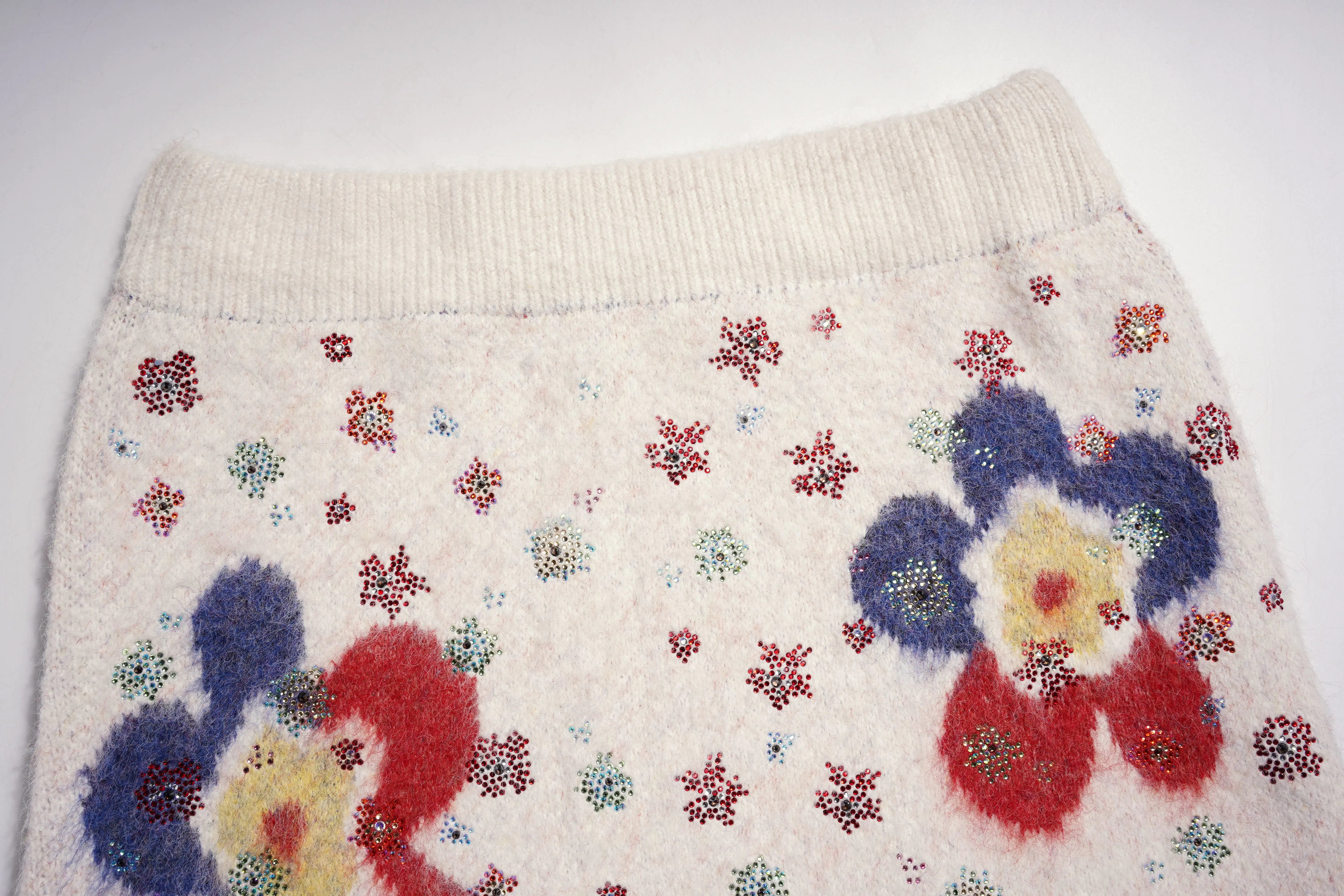 Knitted fabric with colorful flower patterns on a white background, TCH Beige Floral Rhinestone V-Neck Sweater & Wool Mini Skirt Set