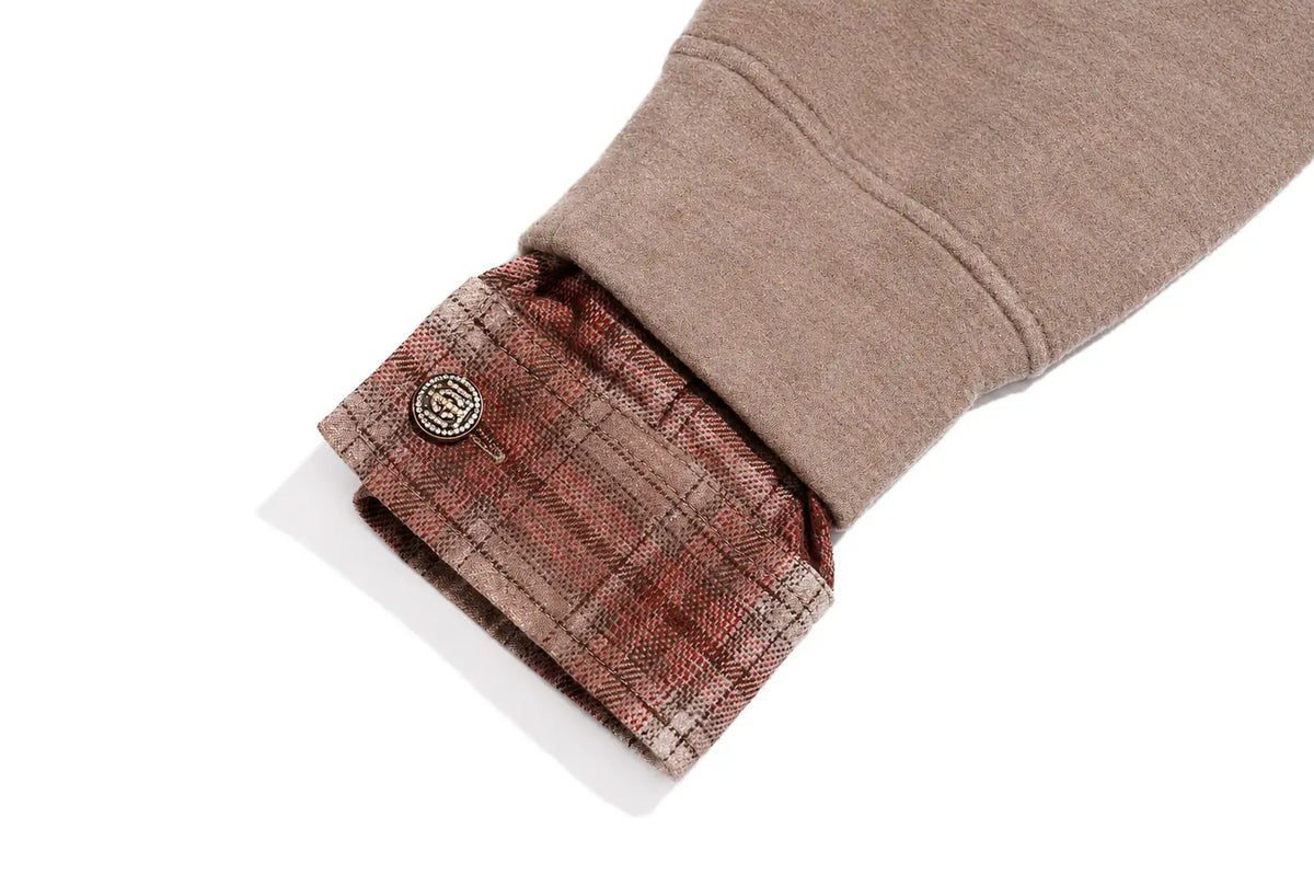 Close-up of a beige or taupe sweatshirt sleeve with a buttoned plaid shirt cuff in muted red, brown, and beige tones, shown on a white background. TCH Beige Teddy Bear Rhinestone Layered Hoodie Sweatshirt