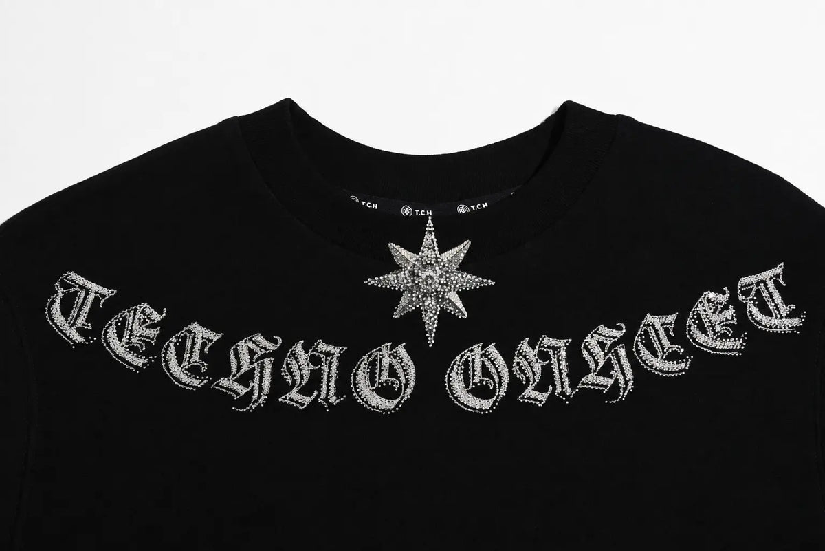 Black crewneck sweatshirt featuring 'TECHNO GANGST' and a star emblem embellished with silver rhinestones, shown against a plain white background. TCH Black Old English Techno Graphic Sweatshirt