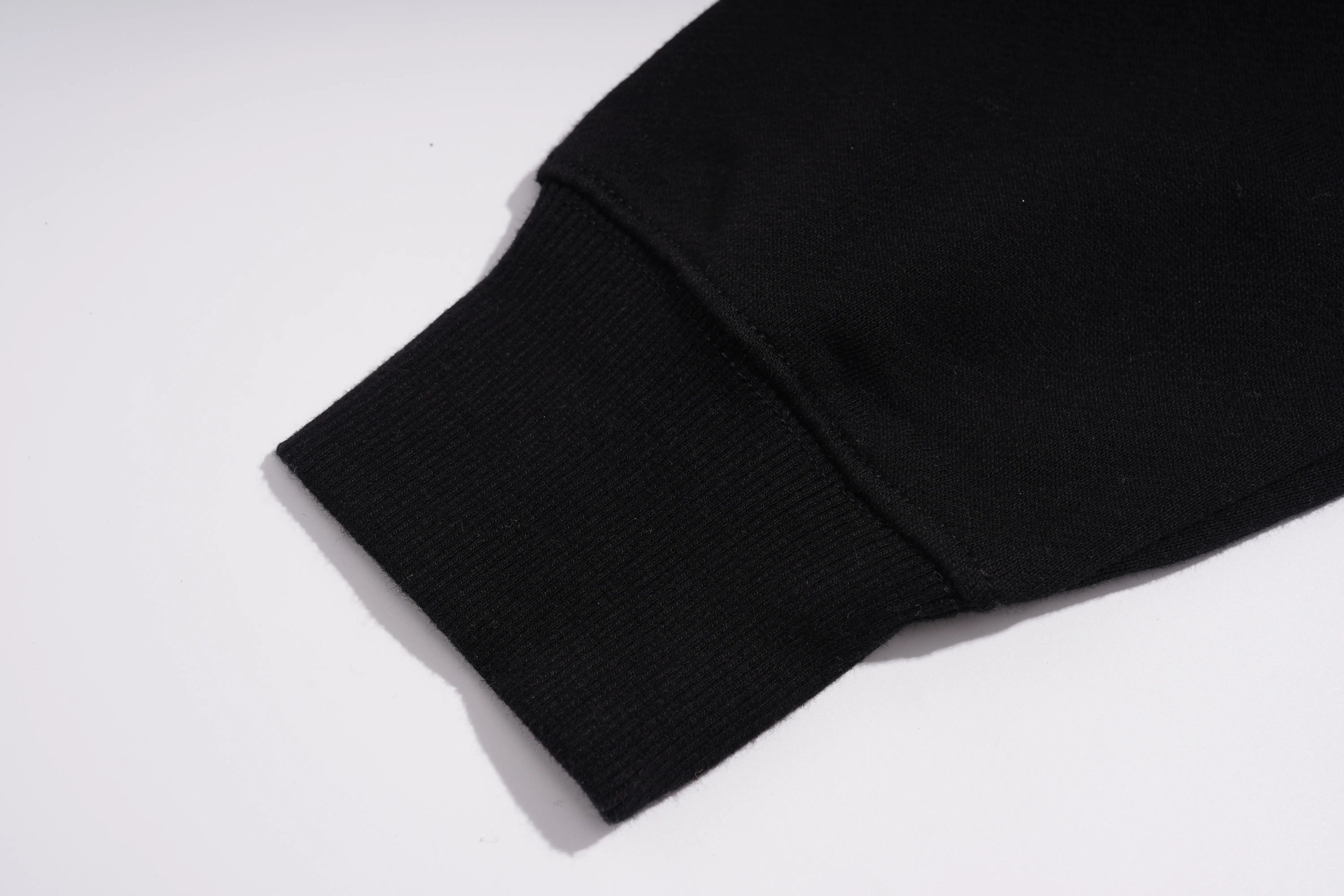 Close-up of a black ribbed knit cuff, likely on a sweatshirt or jacket sleeve, photographed on a plain white background. TCH Black Panda Rhinestone Sweatshirt