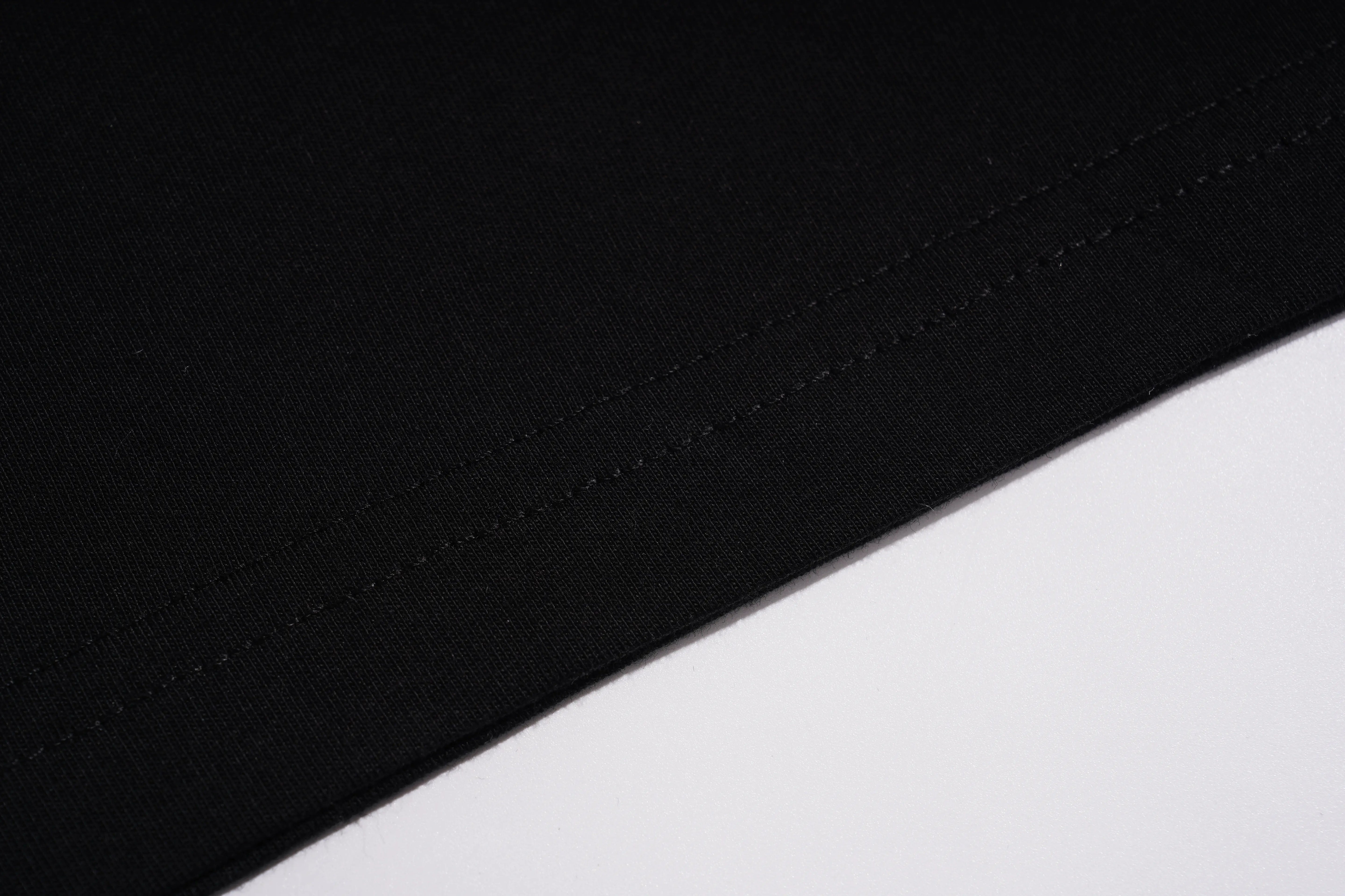 Close-up of a black fabric surface with visible stitching along a diagonal edge against a white background. TCH Black Rhinestone Corset Graphic T-Shirt