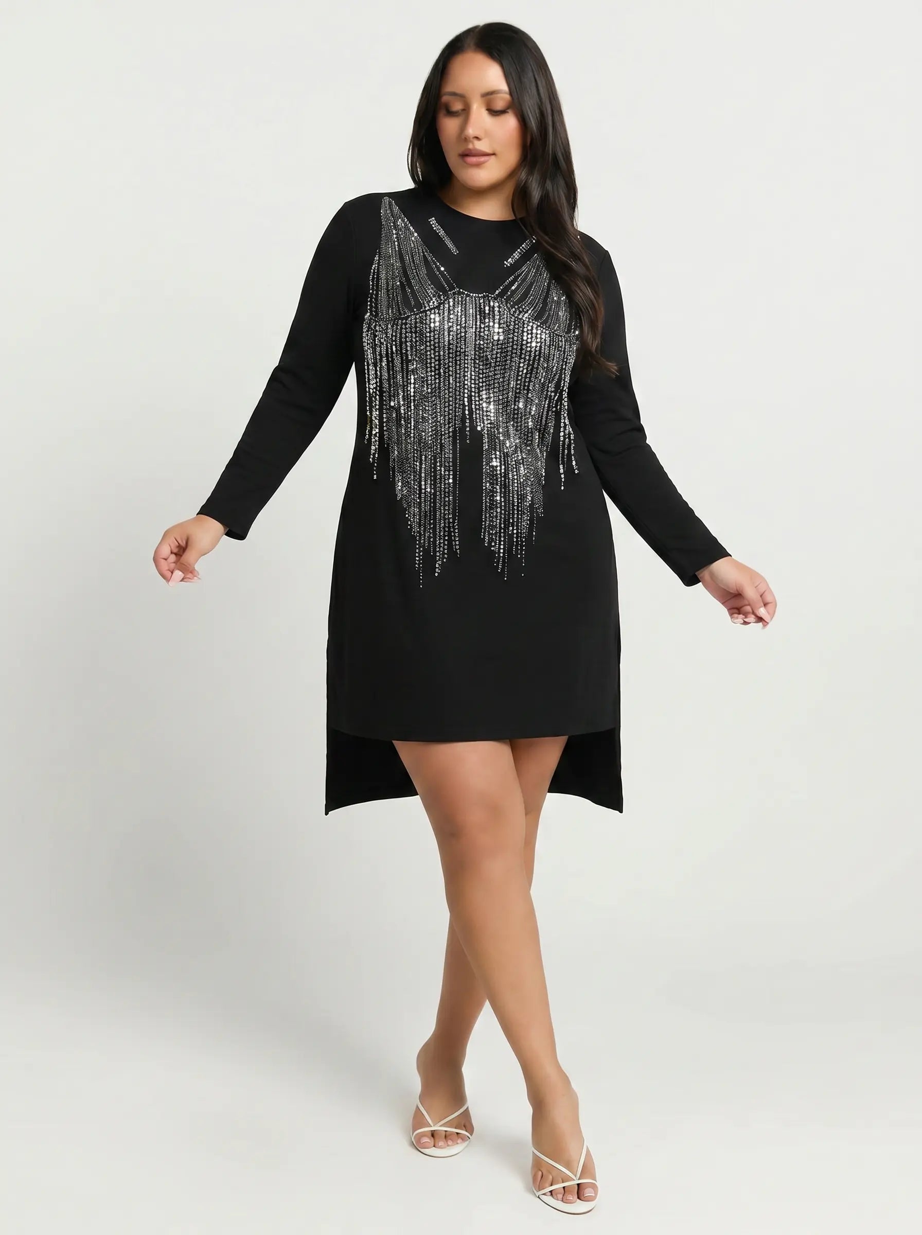 A woman modeling a black long-sleeve mini dress with a silver fringe embellishment across the chest, posed against a light gray studio background. TCH Black Rhinestone Fringe Detail Long Sleeve Mini Dress