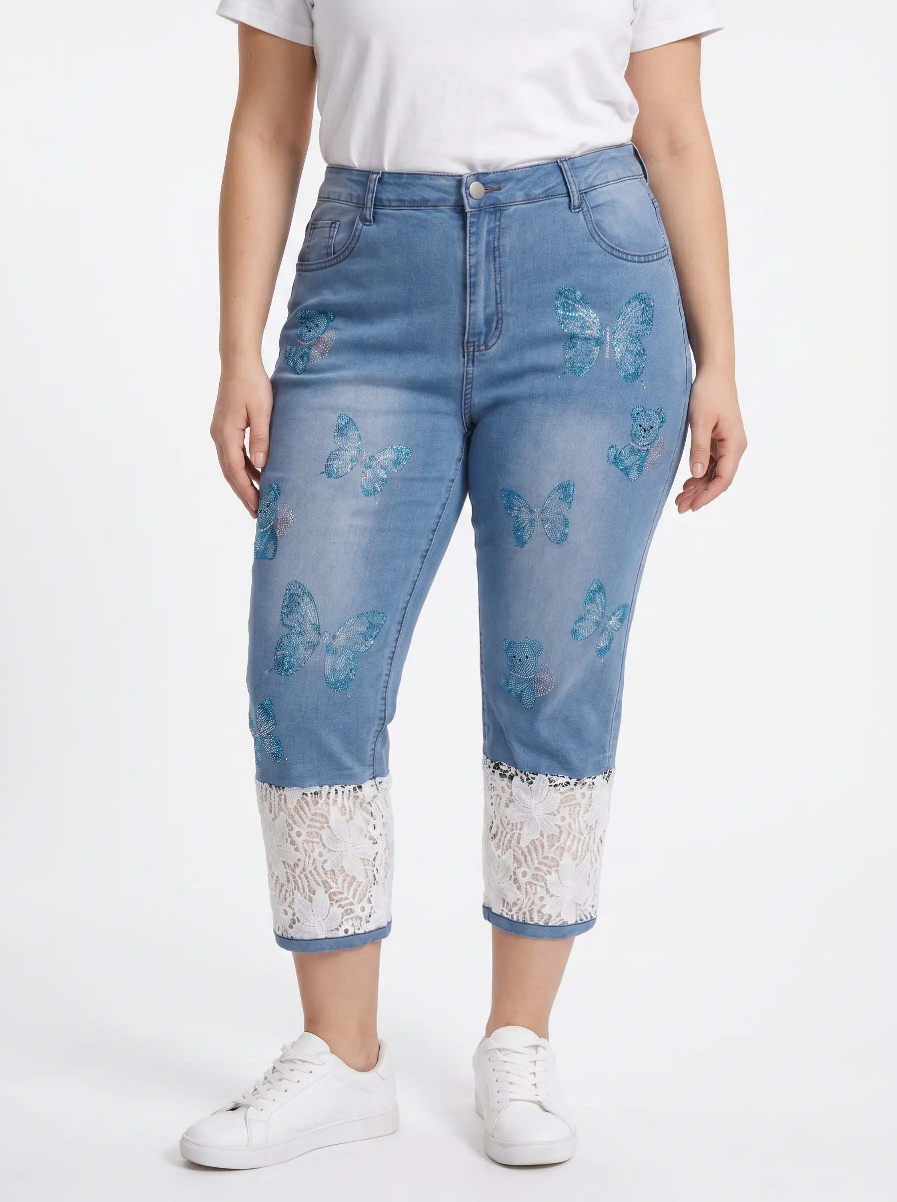 A model wearing light blue cropped denim jeans with blue butterfly prints and white lace trim at the hem, paired with a white t-shirt and white sneakers against a white studio background. TCH Blue Butterfly & Teddy Bear Lace Hem Denim Jeans