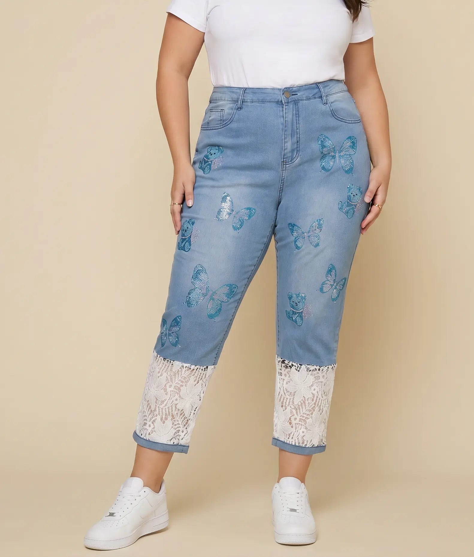 A model wearing light blue denim jeans with blue butterfly prints and white lace trim at the hem, paired with a white t-shirt and white sneakers against a beige background. TCH Blue Butterfly & Teddy Bear Lace Hem Denim Jeans