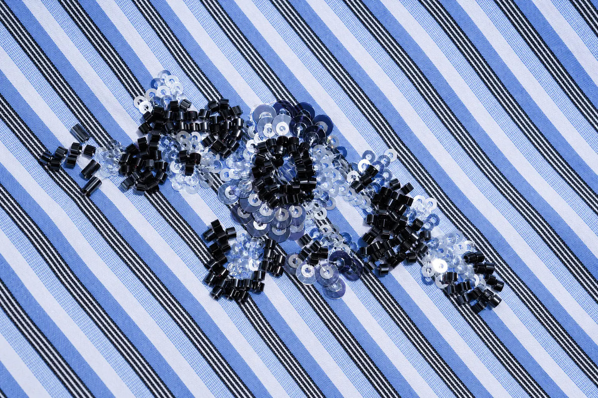 Black and silver sequins arranged to spell 'LOVE' on a blue and white striped fabric background. TCH Blue Floral Embroidered Pinstripe Shirt