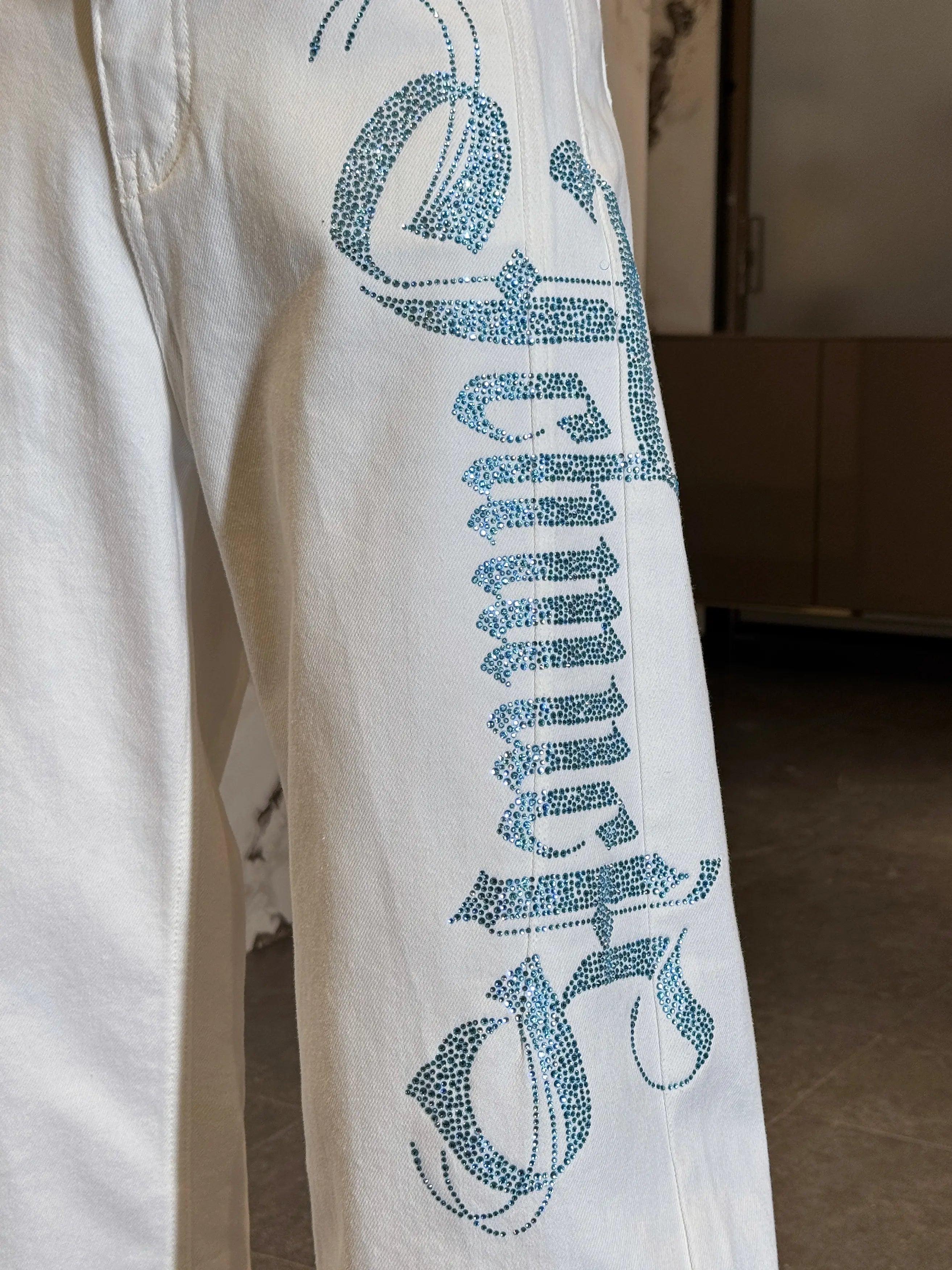 White pants with blue text and graphics on a plain background, TCH Blue Rhinestone Logo & “TchmucH” White Denim Jeans