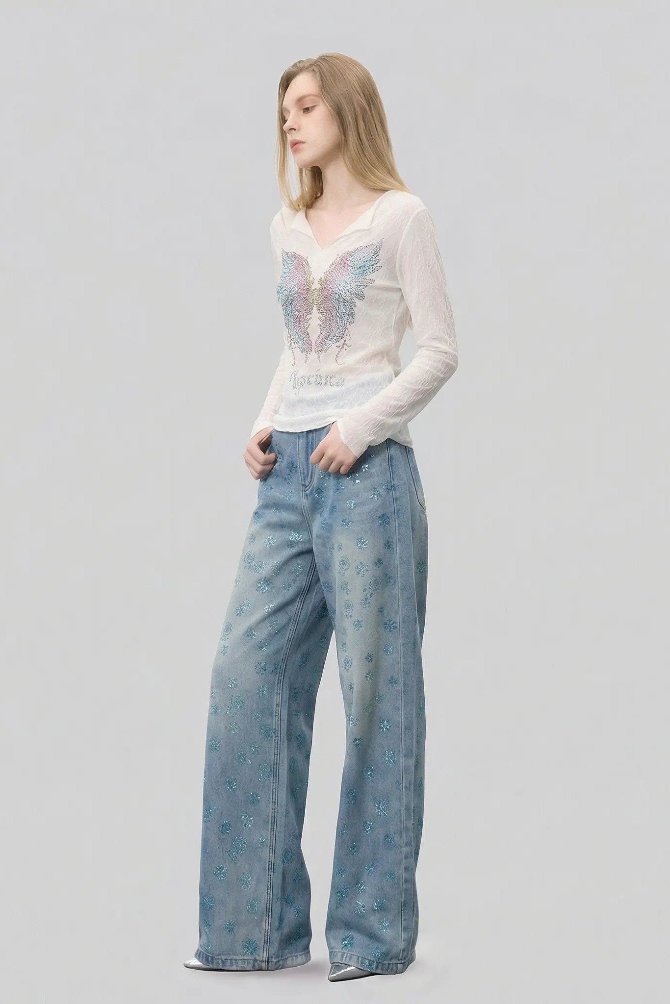 Woman wearing a white blouse with butterfly design and blue jeans on a gray background, TCH Blue Snowflake Rhinestone Denim Jeans