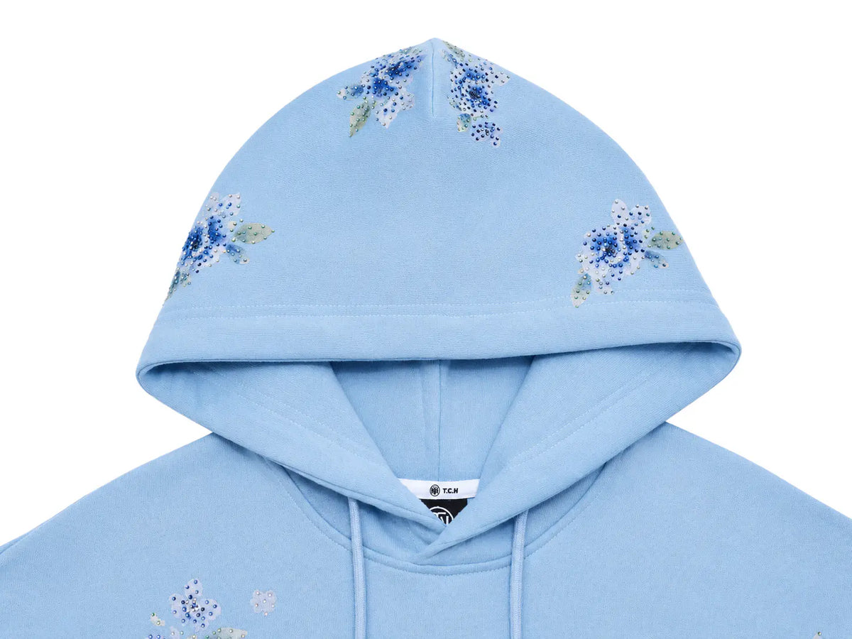 A light blue hooded sweatshirt featuring blue and white floral embroidery on the hood and upper chest, shown against a plain white background. TCH Blue Teddy Bear Floral Rhinestone Hoodie