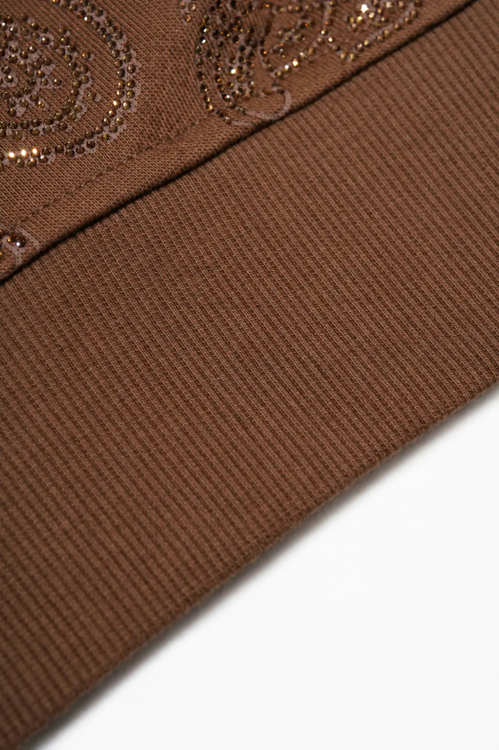 Close-up detail of a brown ribbed knit fabric with metallic embroidered swirl patterns along the top edge, shown against a white background. TCH Brown Rhinestone Paisley Zip Up Hoodie