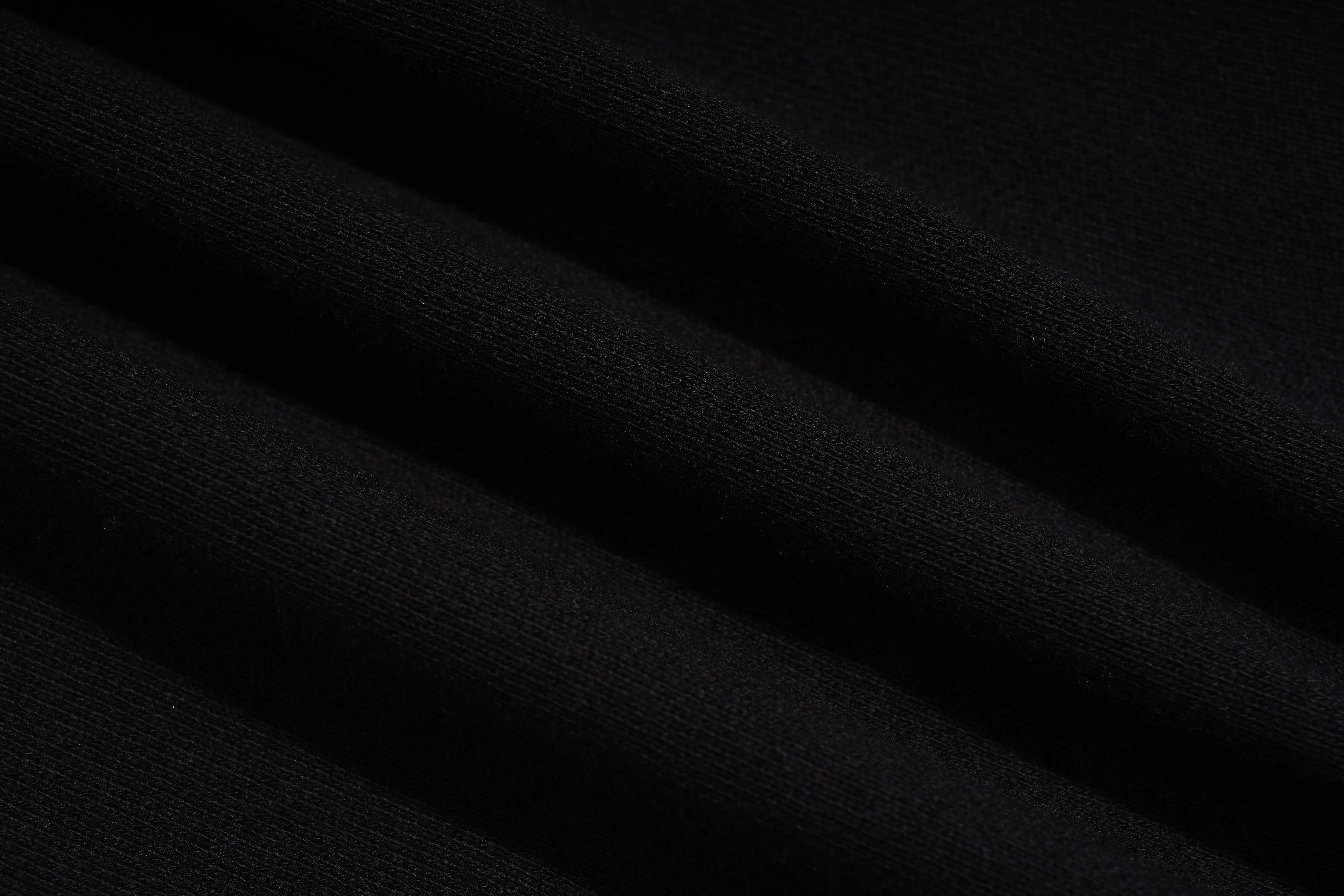 A close-up of black fabric with soft diagonal folds showing a fine knit texture. TCH Butterfly Rhinestone Graphic Black Jogger Pants