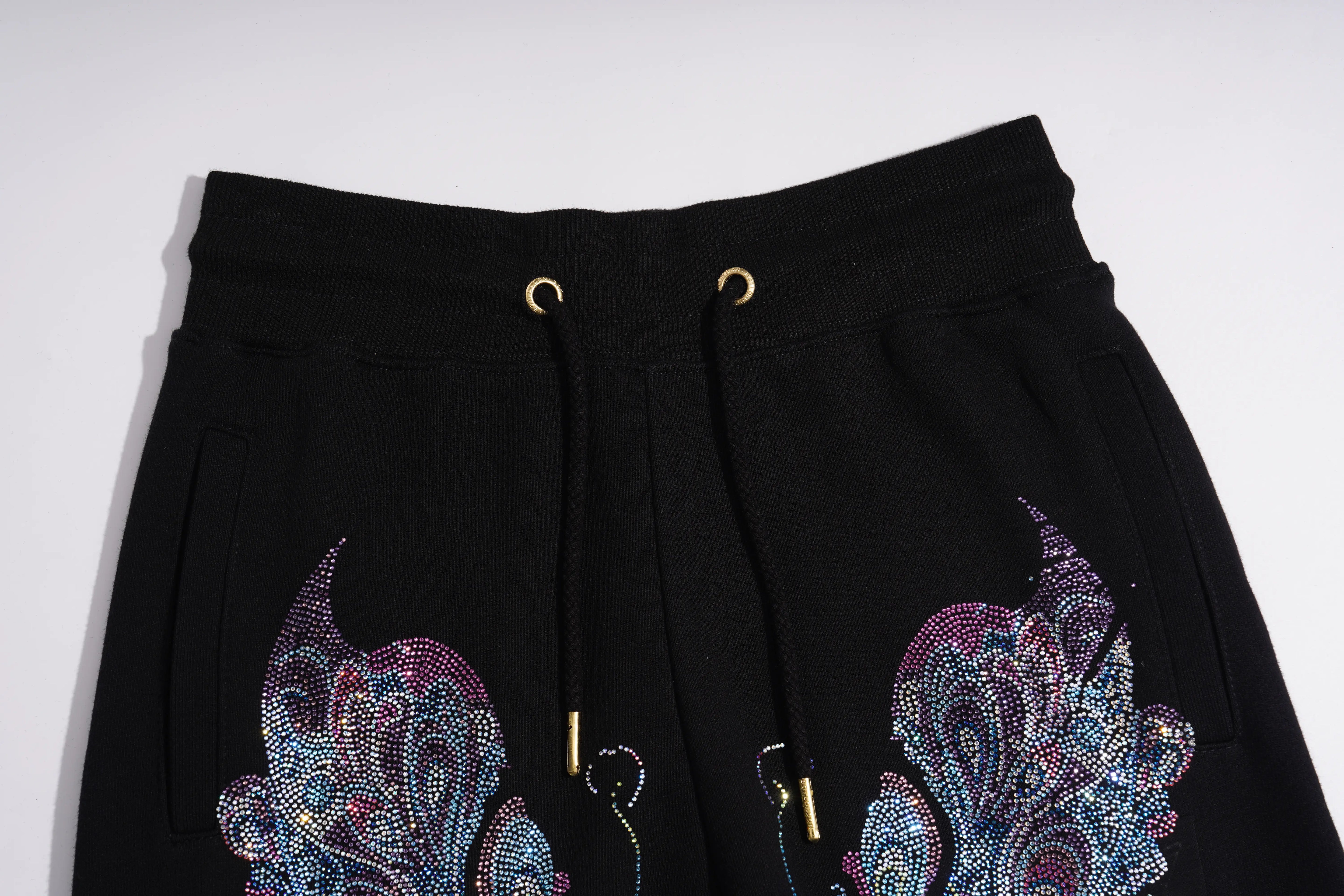 Black sweatpants featuring a drawstring waist with gold metal rings and gold-toned tips, decorated with large, colorful rhinestone-embellished butterfly motifs on the lower front panels. TCH Butterfly Rhinestone Graphic Black Jogger Pants