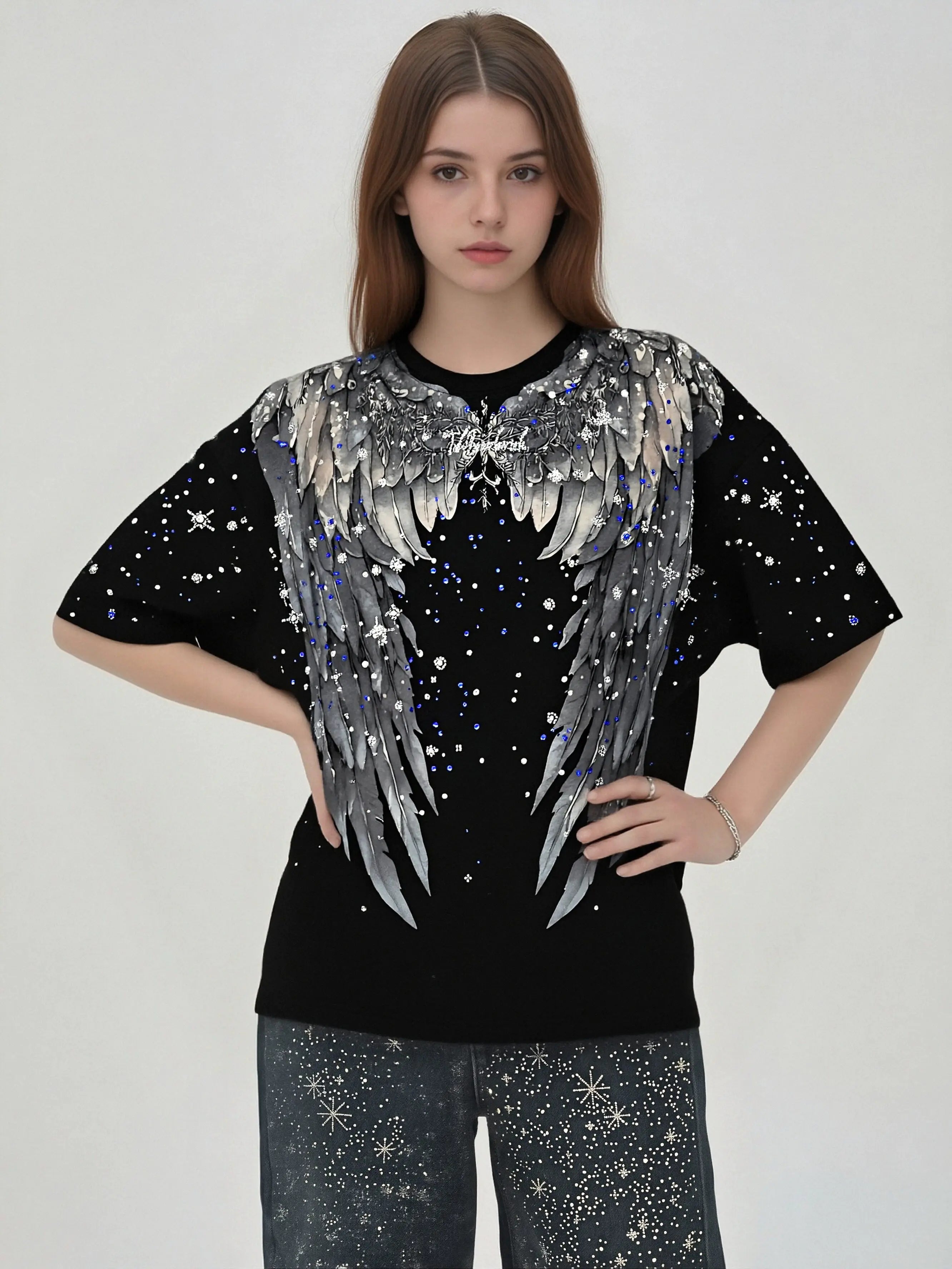 A model wearing a black short-sleeve t-shirt with a large silver and gray angel wing graphic on the front, decorated with white star-like sparkles, paired with matching sparkly pants against a plain light gray background. TCH Celestial Angel Wings Graphic Oversized T-Shirt